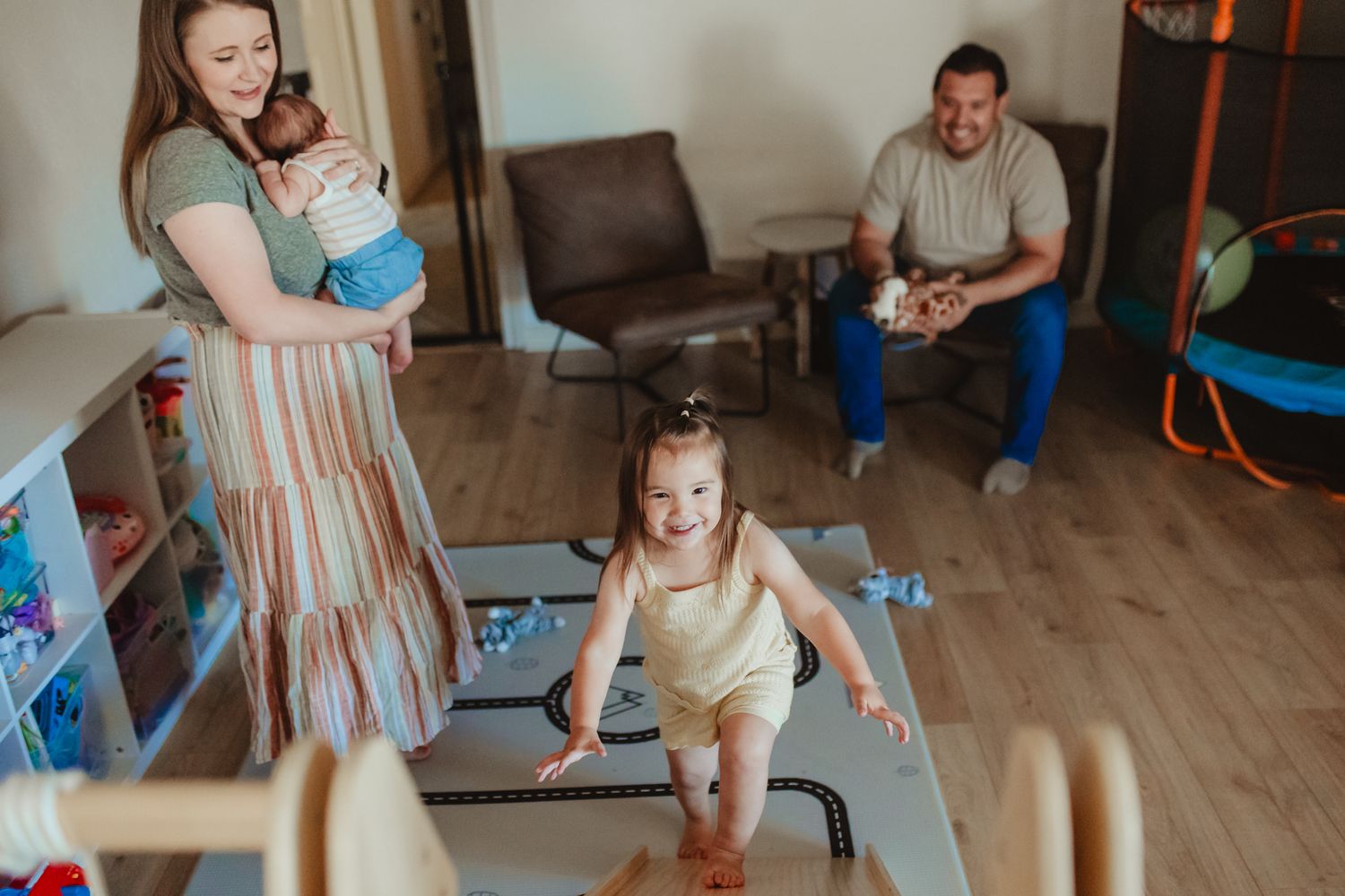 A parent and toddler play together in a living room space during a family activity session.