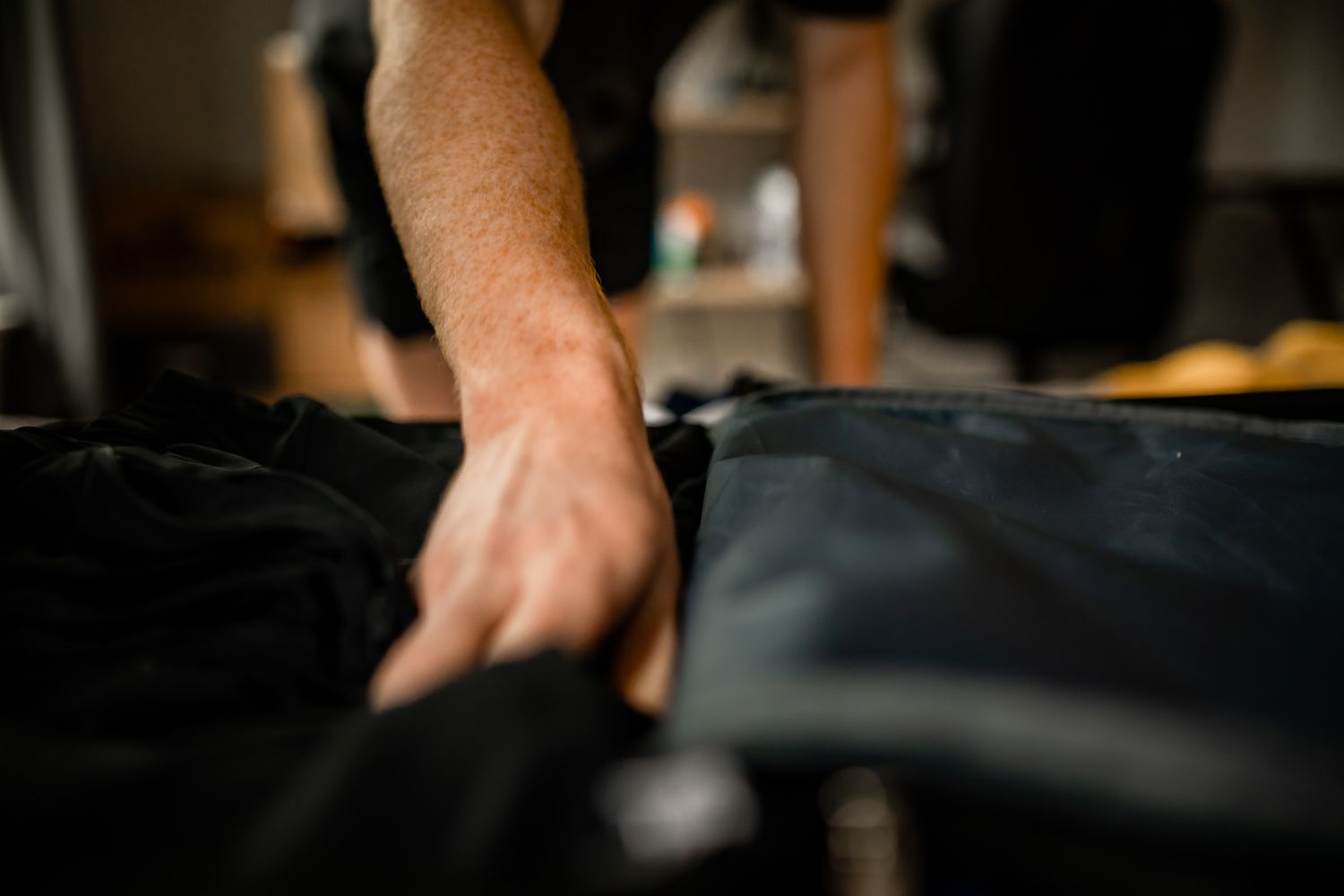Person's hand touching black fabric material.