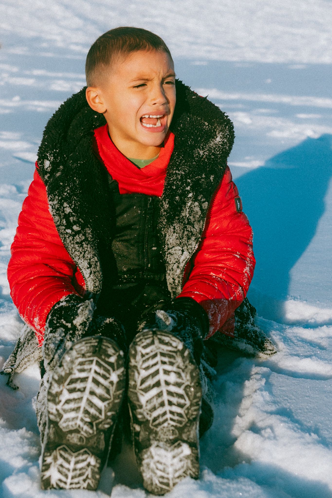Winter fun captured as child in red jacket enjoys playing in deep snow.