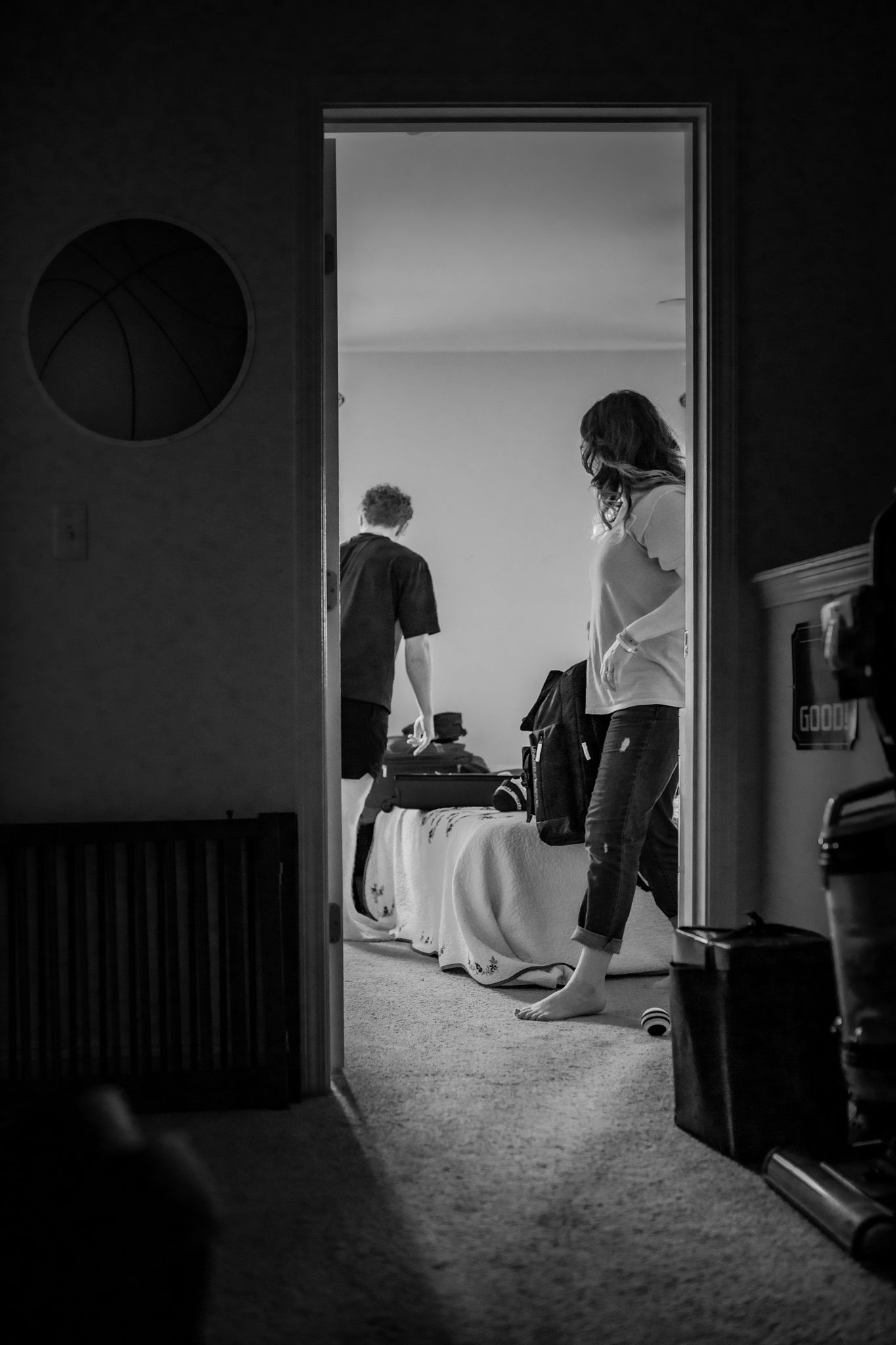 View through doorway showing two people in a bedroom with equipment. In-Home Photography Liz Perez