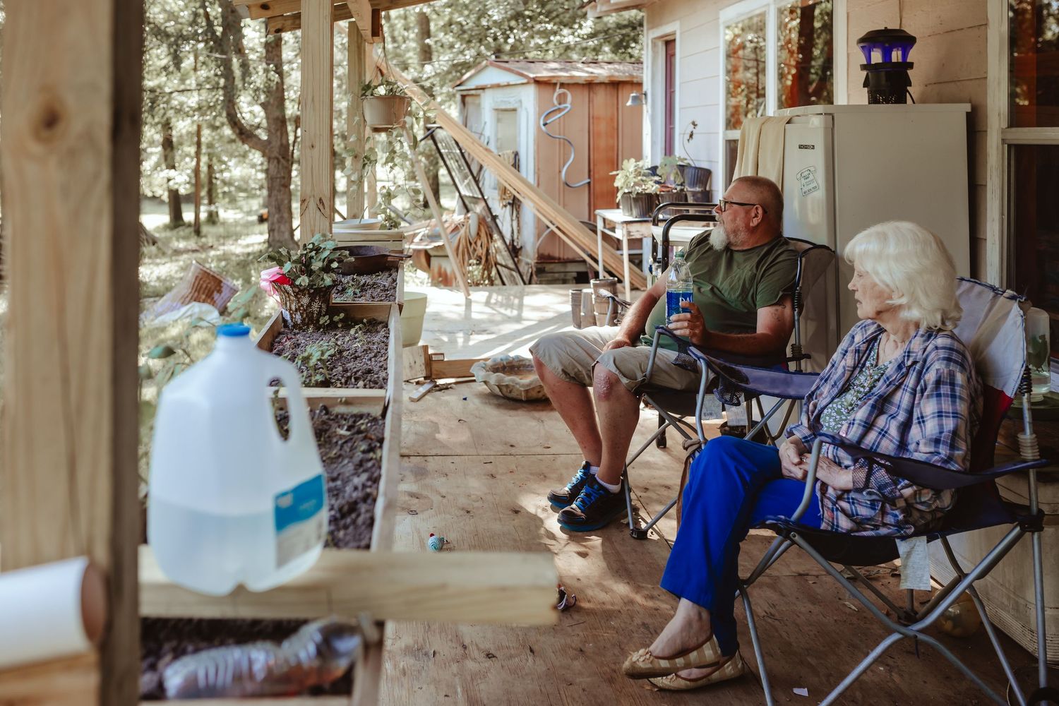 People relaxing on a covered porch with chairs and casual outdoor furniture.