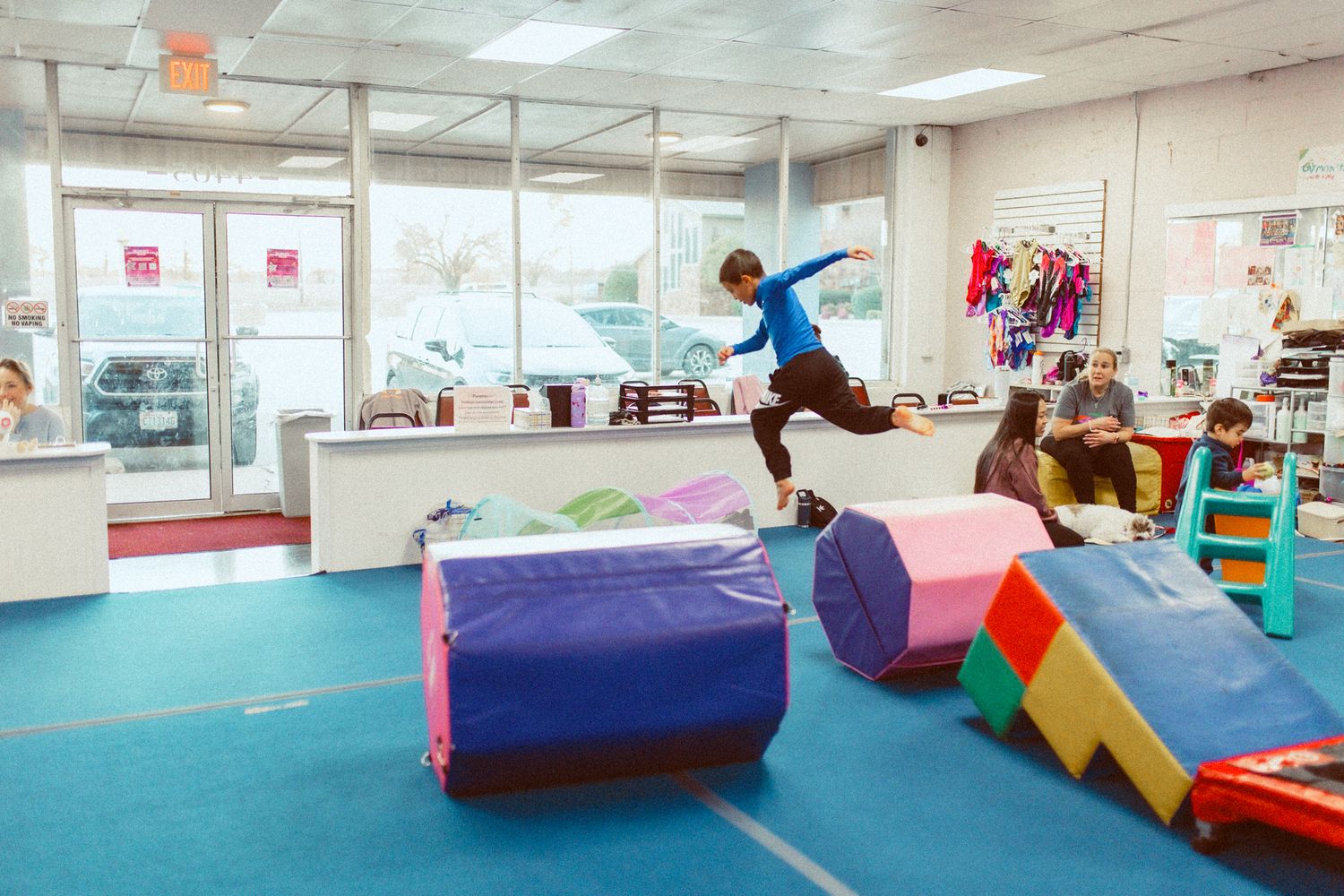 Person jumping over foam blocks and obstacles in a gymnastics training facility.