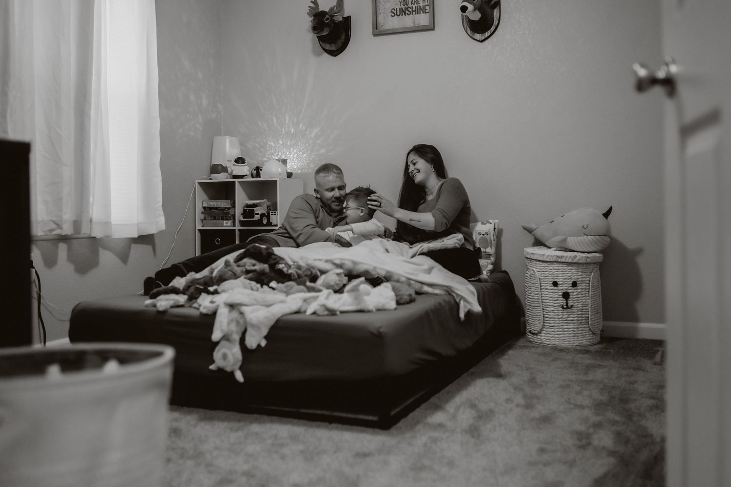 Two people relaxing on a bed in a cozy bedroom with wall decorations.