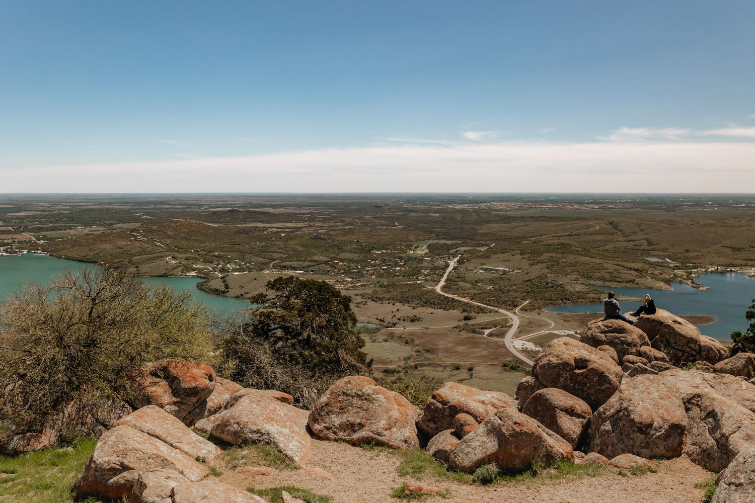 Panoramic landscape view of rocky terrain and distant water under blue sky.