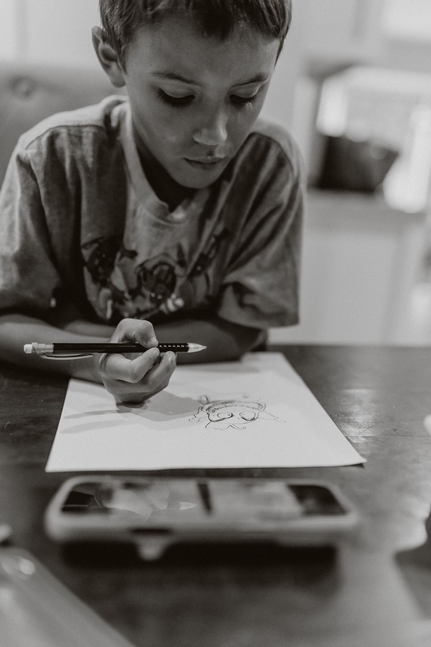 Black and white photo series showing a student drawing on a digital tablet with focused concentration. In-Home Photography Liz Perez