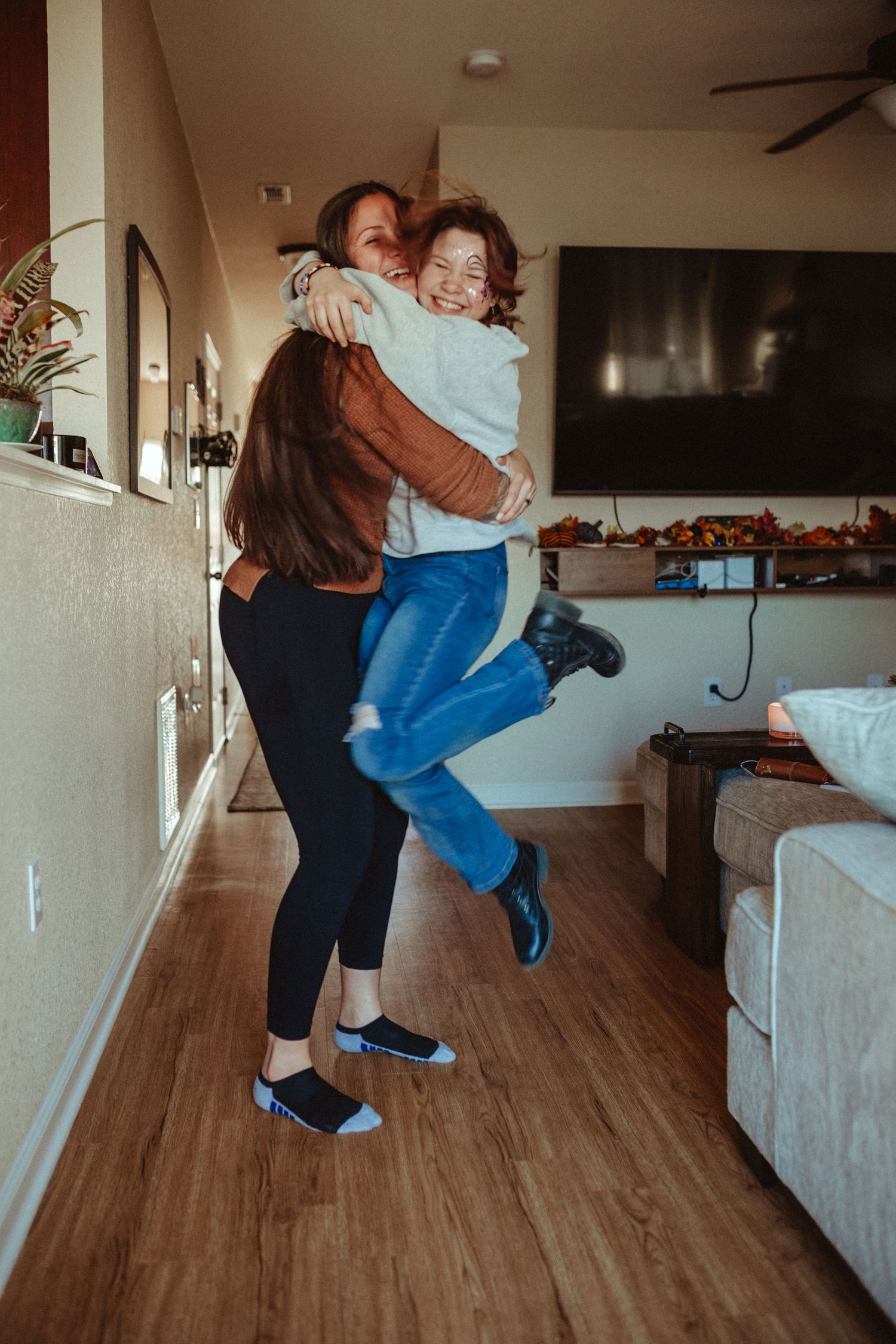 Two people sharing a joyful embrace and jumping in a living room.