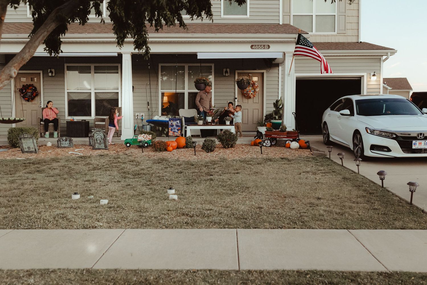 A suburban house decorated with fall pumpkins and Halloween decor on the front porch.