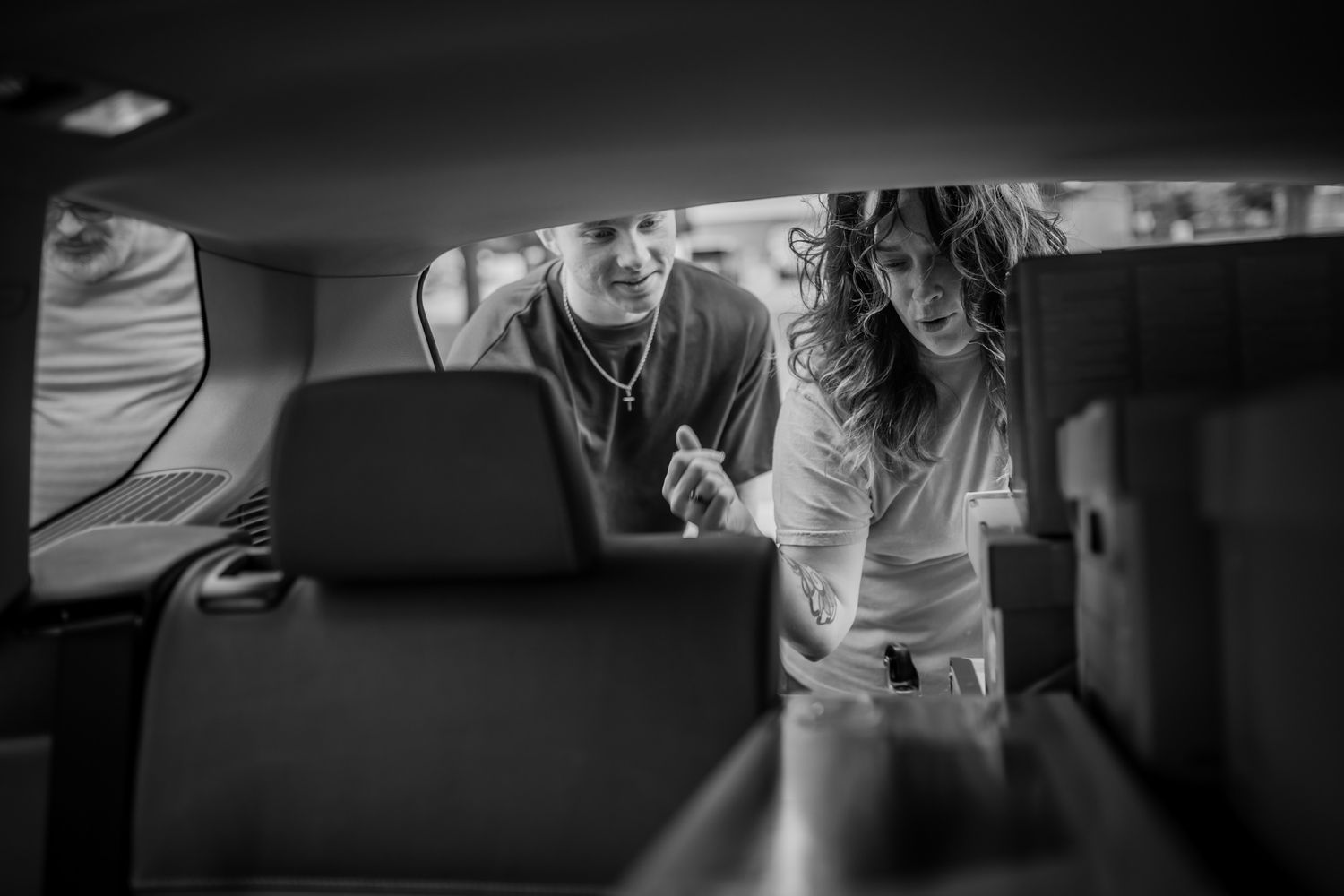 Group gathered around a vehicle having an animated discussion and gesturing at details. In-Home Photography Liz Perez