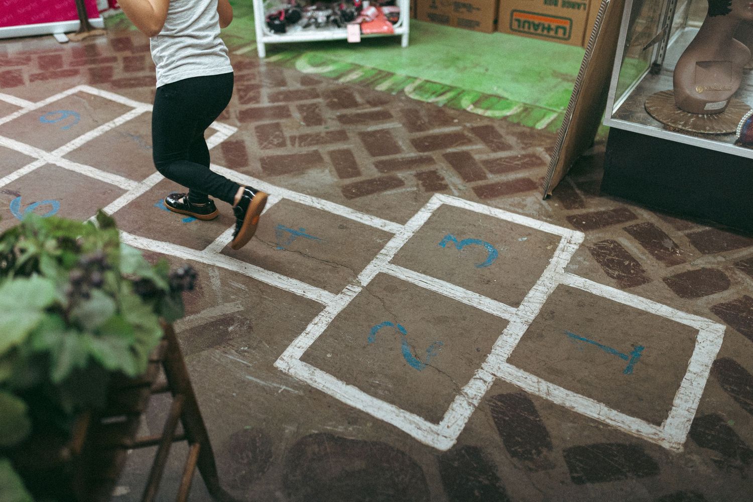 Hopscotch game lines drawn in chalk on a paved outdoor surface with numbers and squares visible. In-Home Photography Liz Perez