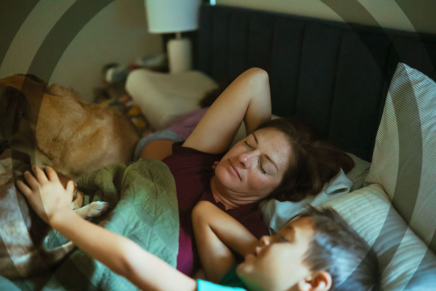 Person sleeps peacefully in bed beside a sleeping dog while bathed in soft glowing light. Documentary Photographer Liz Perez