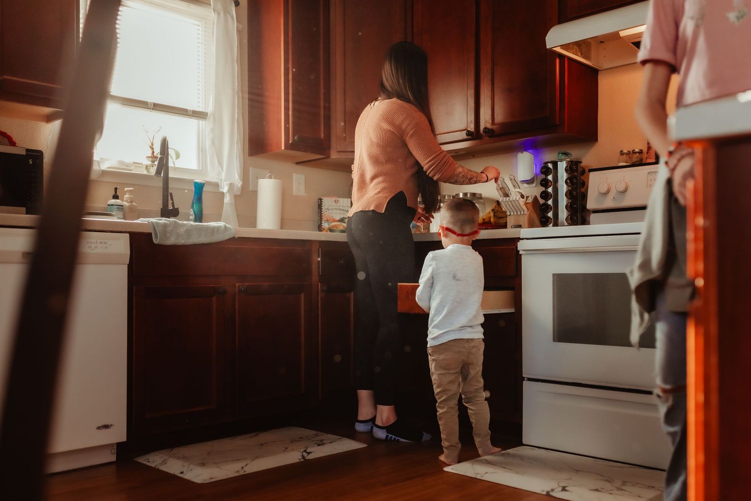 Parent and child cooking together in a kitchen with warm lighting.