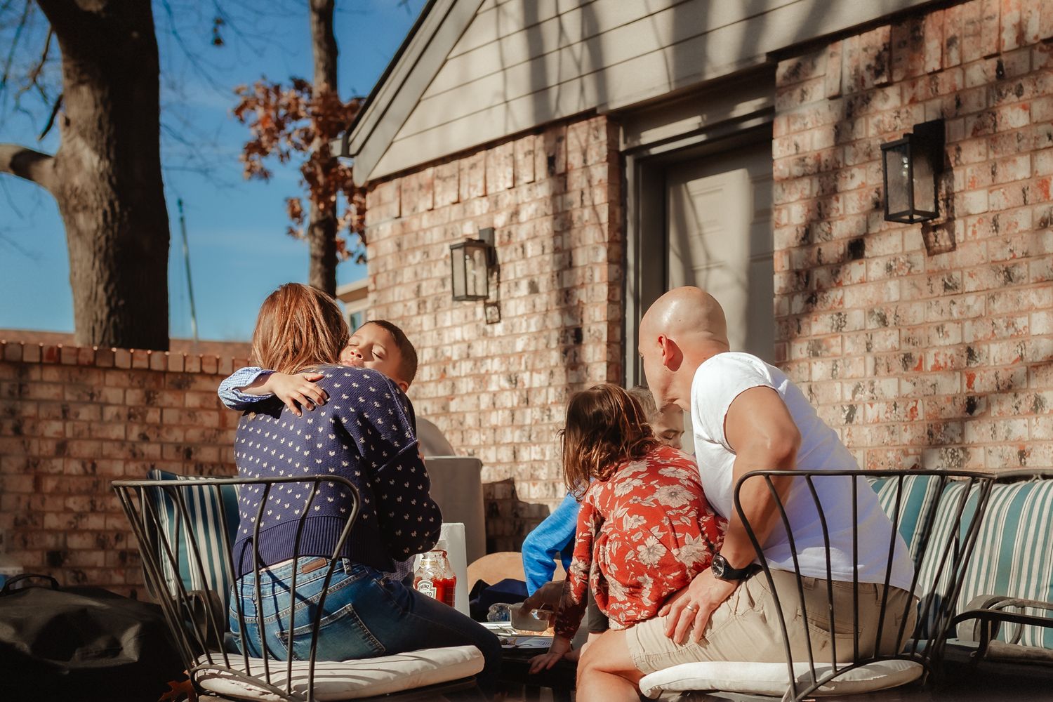 Family enjoying quality time together on a cozy outdoor patio with brick walls.