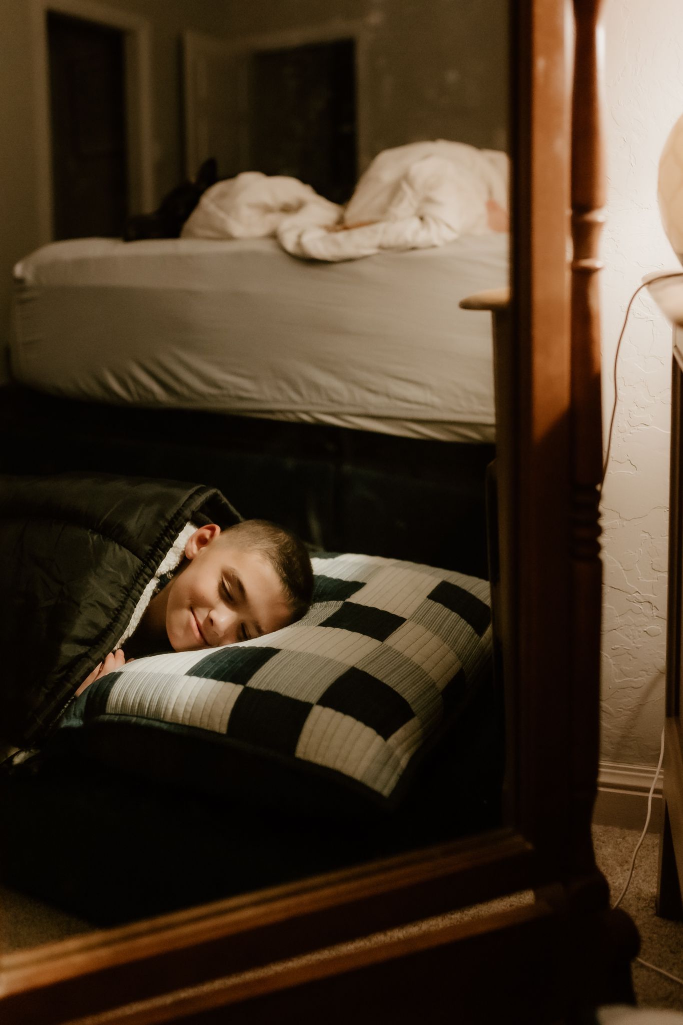 A dimly lit bedroom with buffalo check pillows and white bedding.