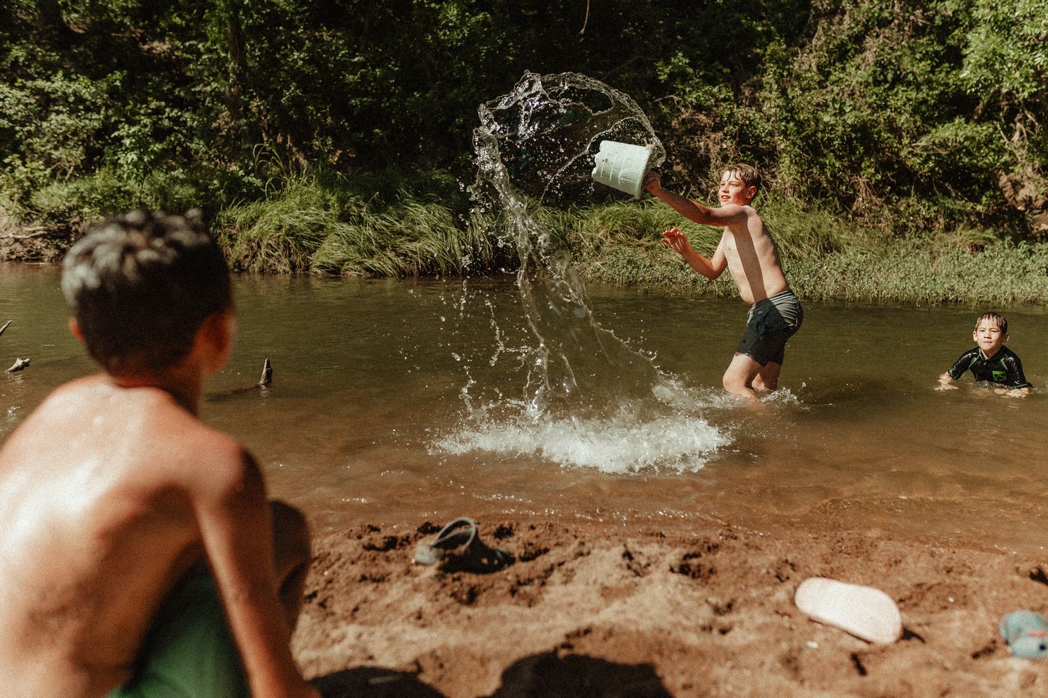 Kids playing in a river with water splashing from thrown objects.
