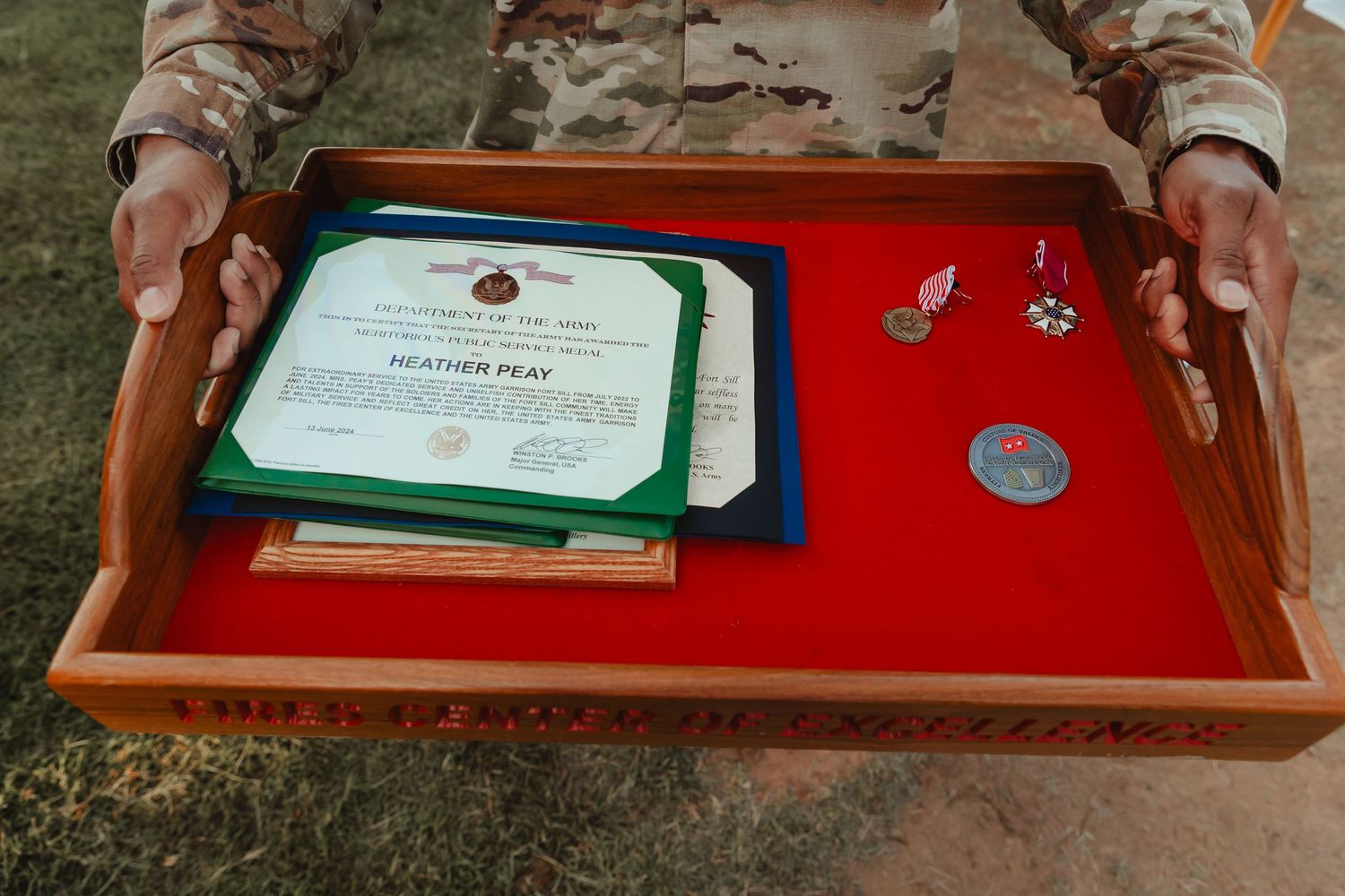 Military service awards, medals, and certificates displayed on a wooden tray with red felt lining.