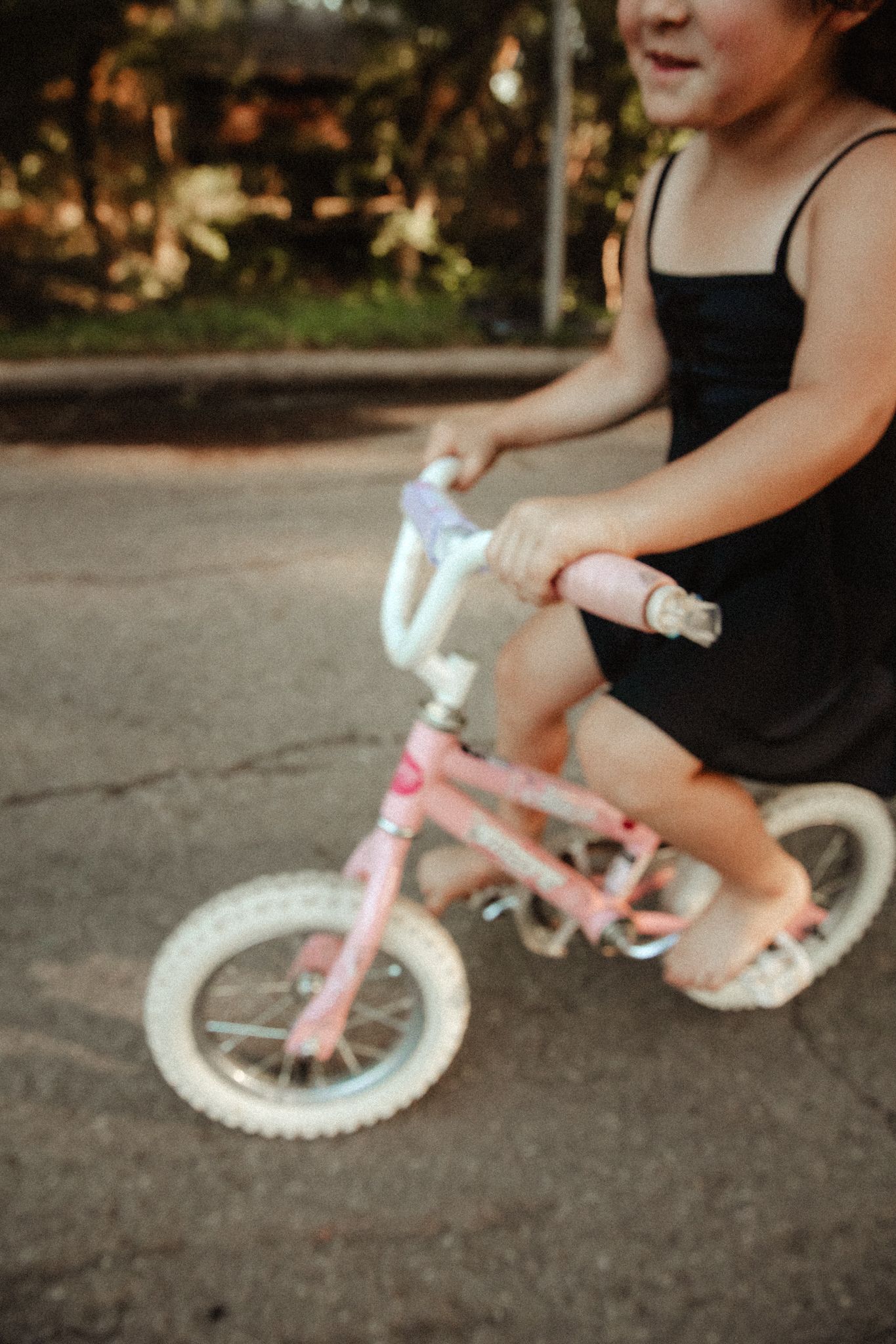 Close-up view of a small pink bicycle wheel on pavement after she's just learned to ride her bike.
