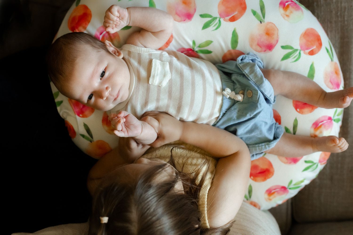 A floral nursing pillow provides comfort on a couch.