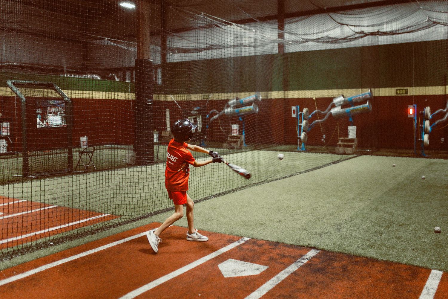 Indoor baseball batting practice setup with nets and screens in low light. In-Home Photography Liz Perez