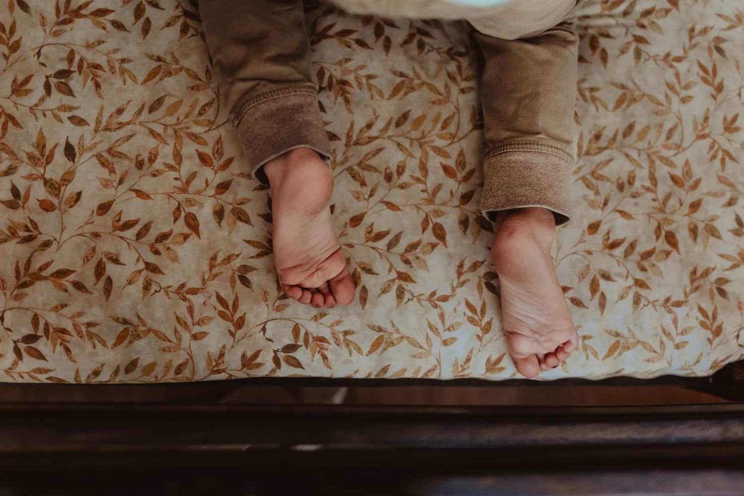 Small feet resting on patterned fabric in natural light.