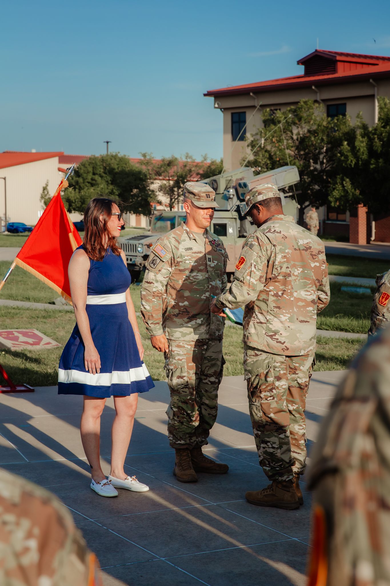 Military service members participate in outdoor physical training exercises on a sunny day.