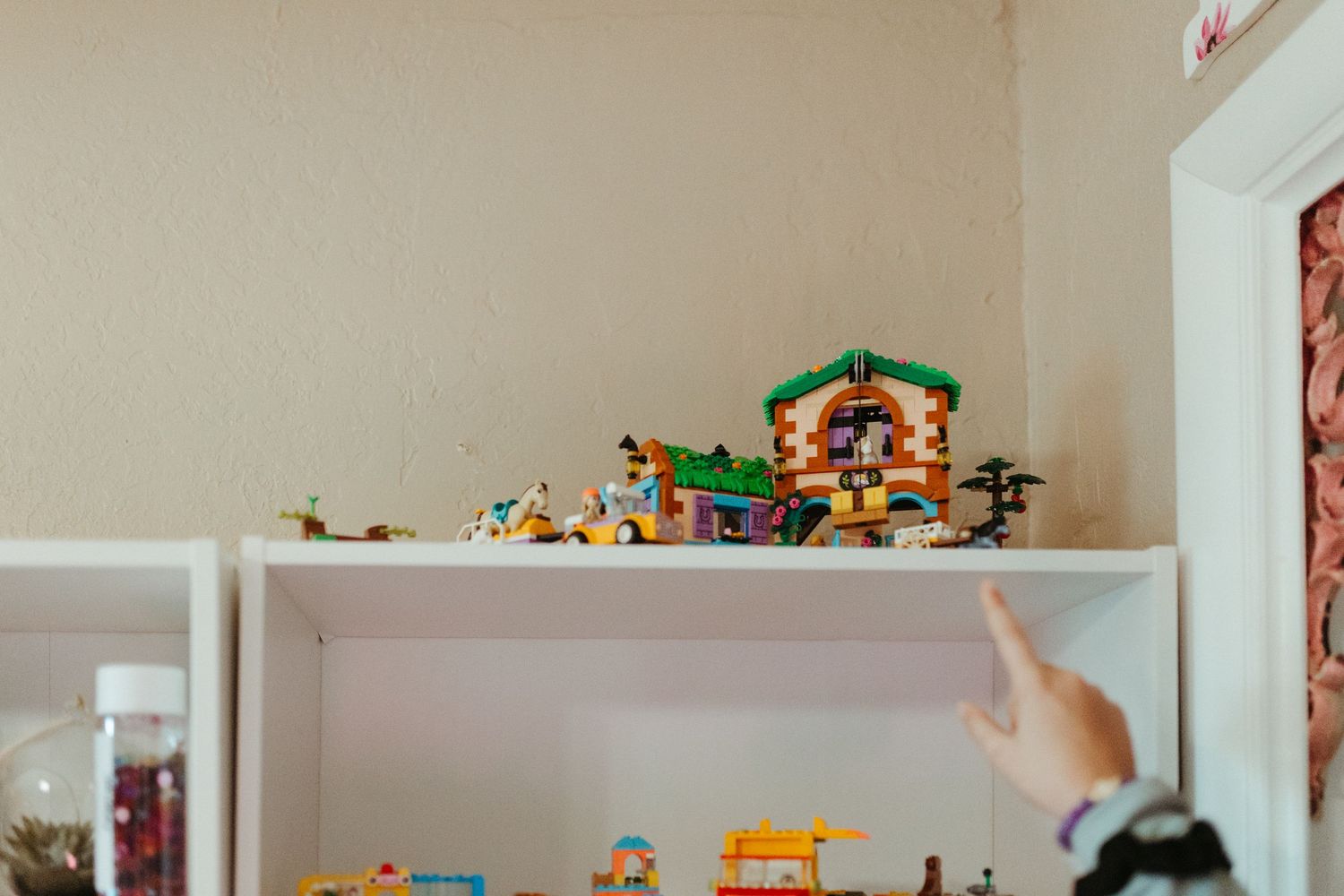 Colorful toy collection displayed on white built-in shelves in a child's room.