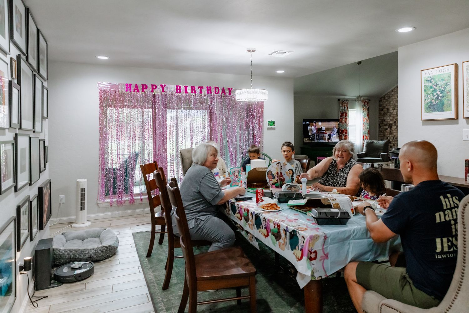 A panoramic view of a basement home gathering with people seated around tables in a casual setting.