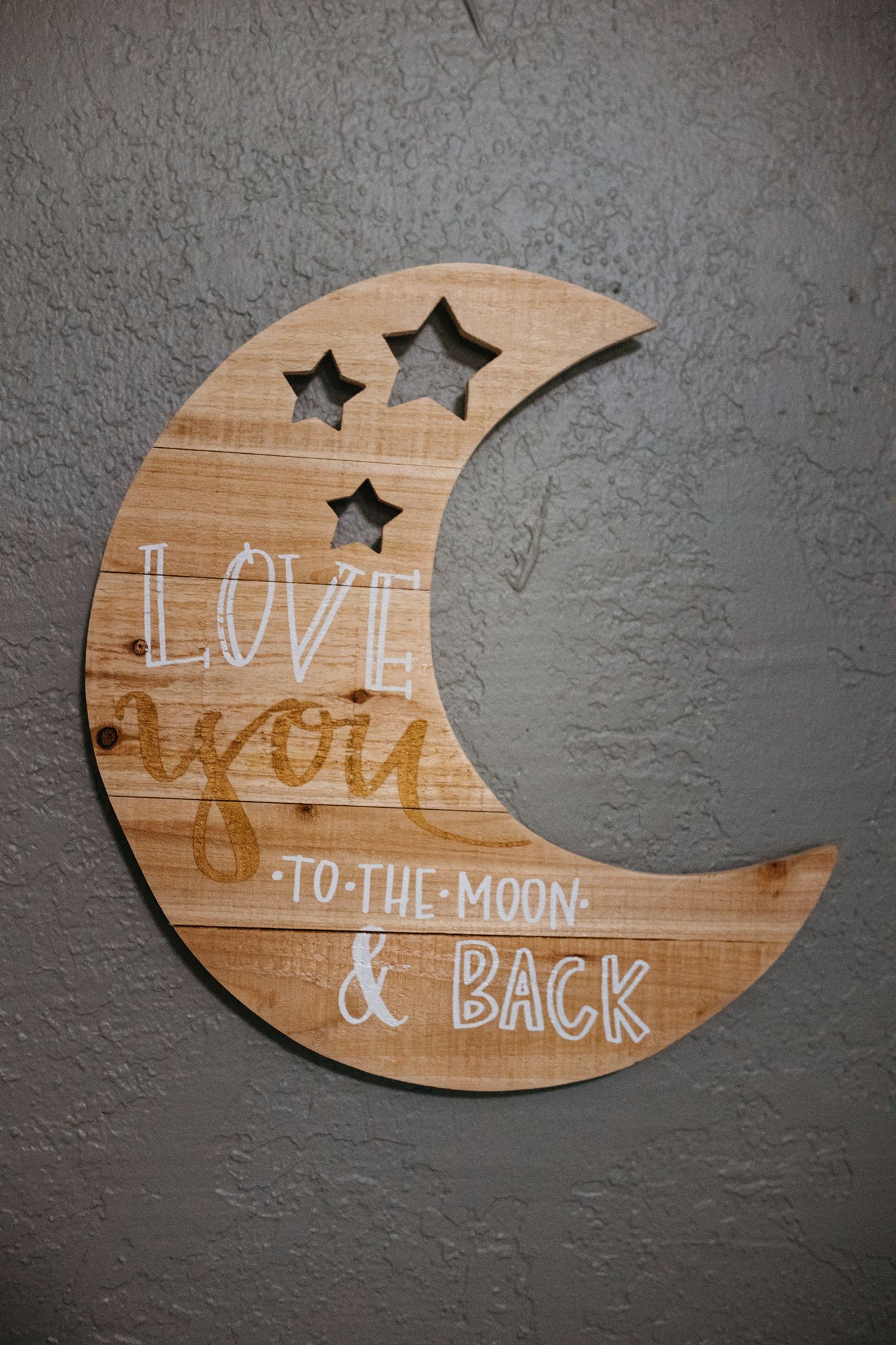 Wooden crescent moon wall decoration with cutout stars and text 'Love you to the moon & back' in rustic style.