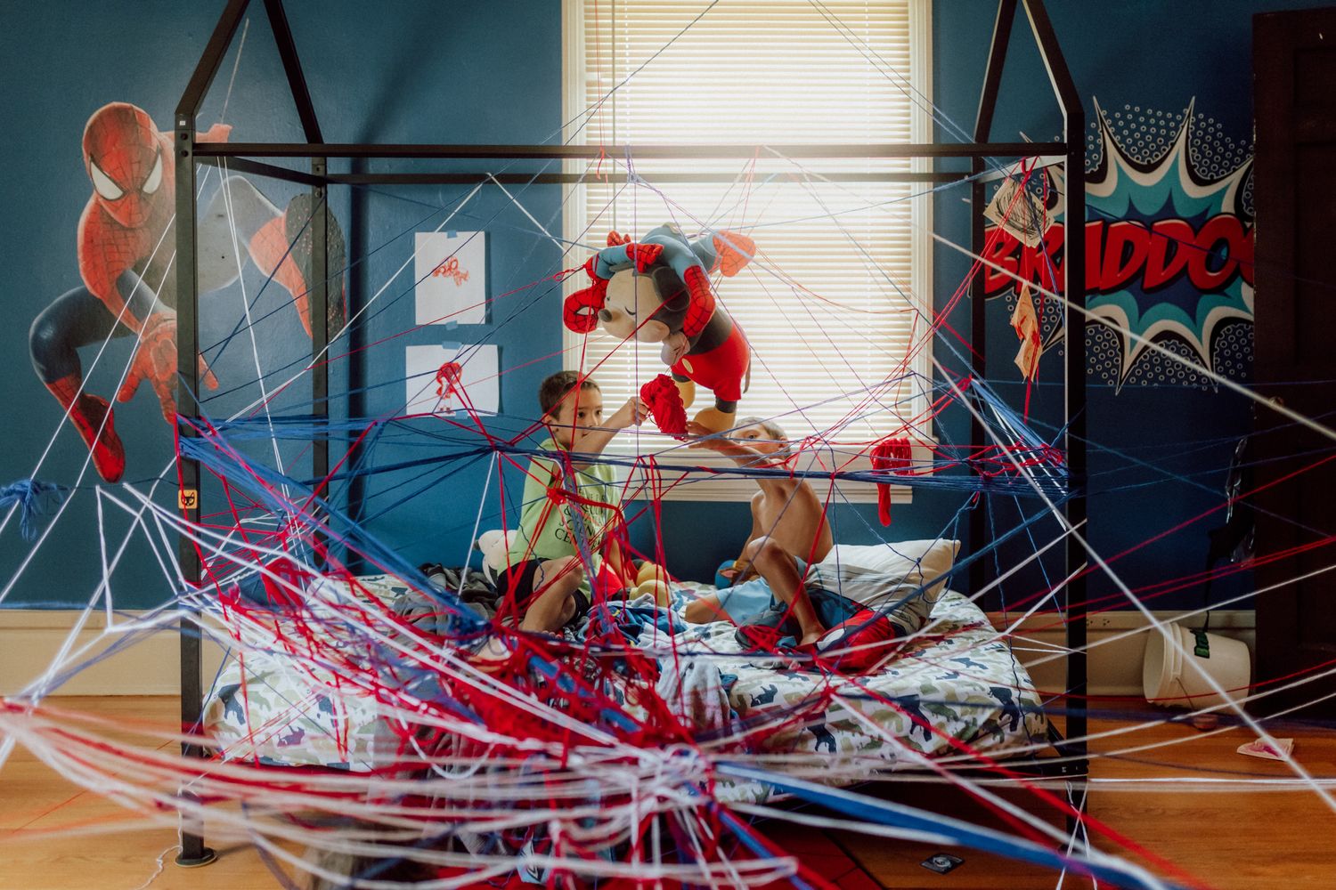Kids that have taken lots of yarn and using their imagination to create a world of spider webs because one person loves Spiderman.