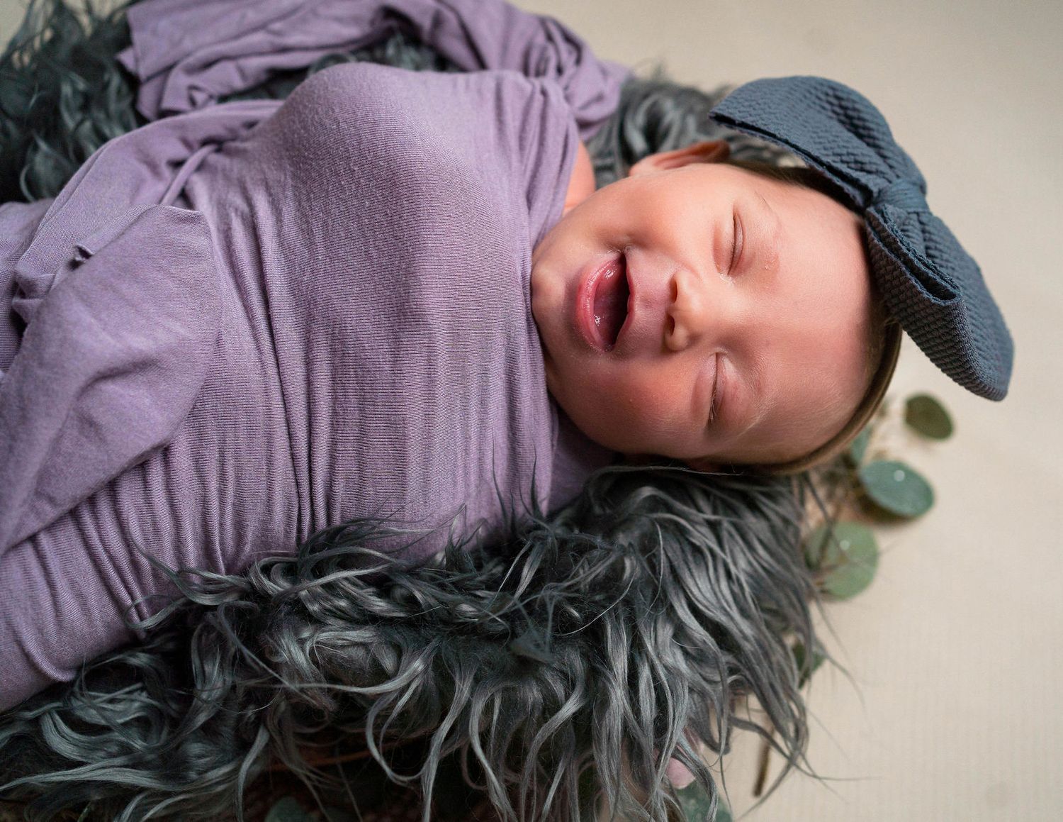 baby smiles on bed during her newborn session located in Warrensburg in the photographers studio