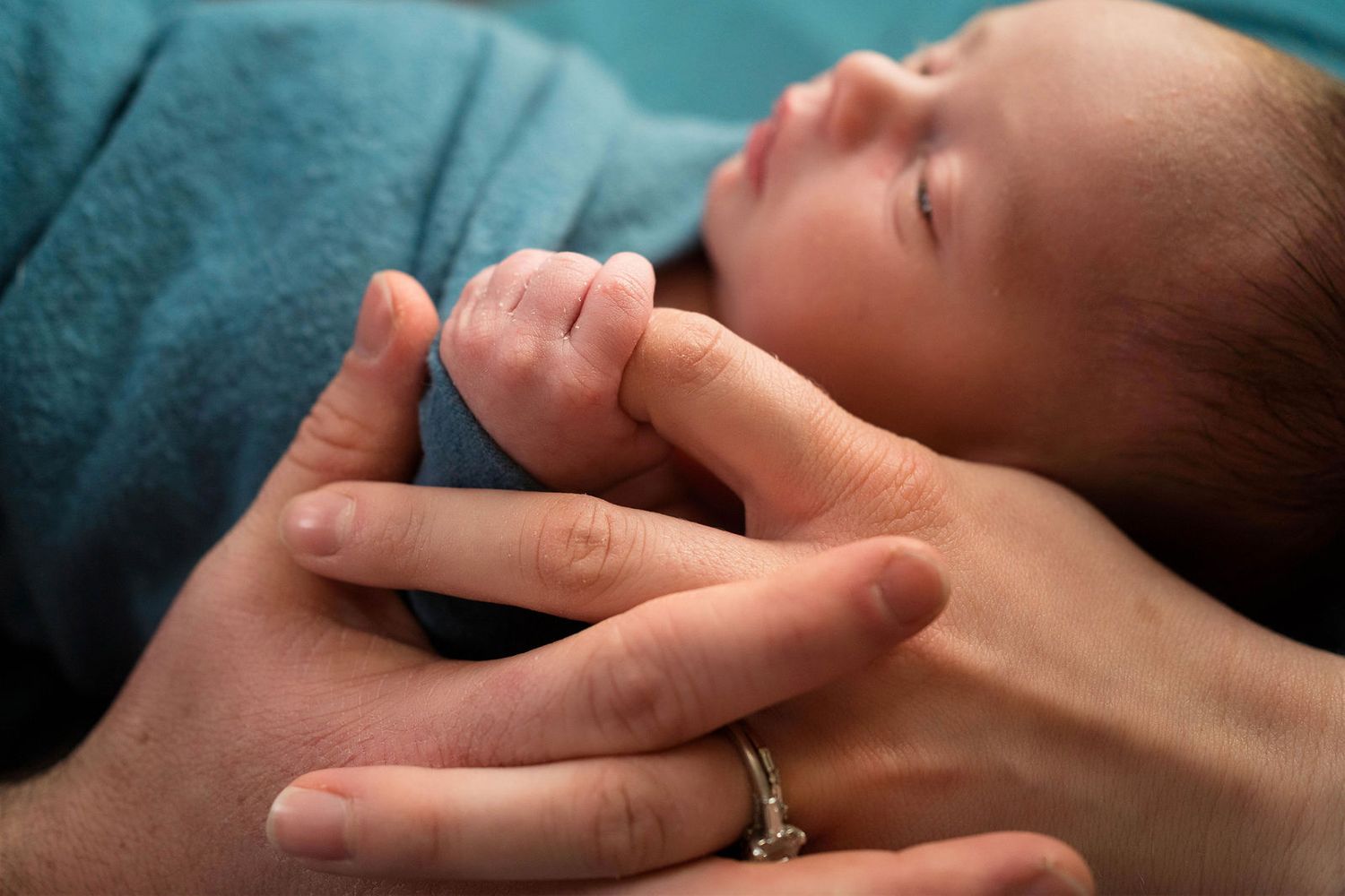 a baby holds his mom's finger during his newborn photos in studio in the photographers studio in Warrensburg