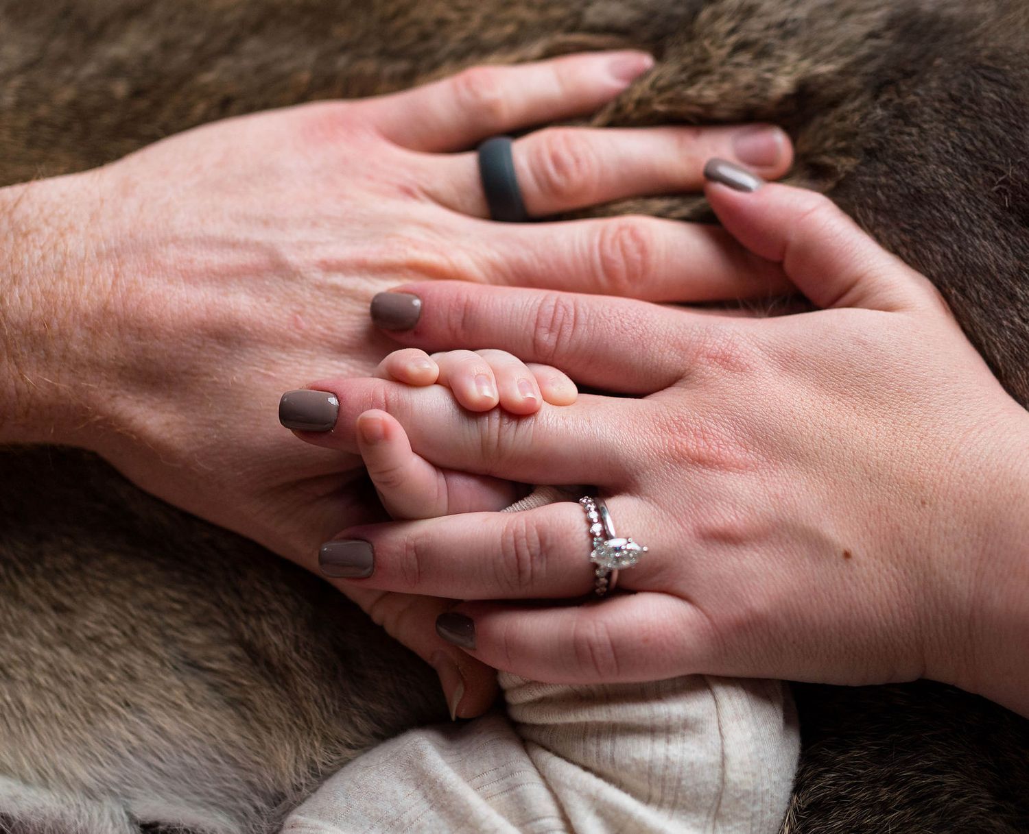 Mom, dad, and baby holding hands during their newborn session in Lee's Summit