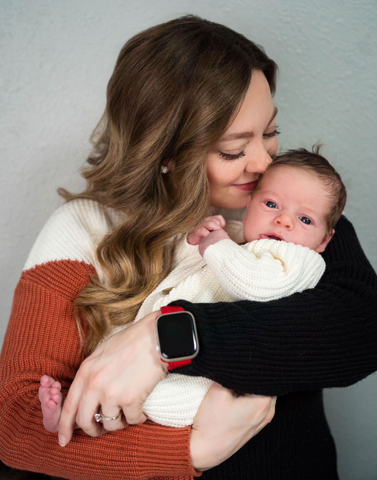 A mom snuggles into her newborn during their in-home newborn photography session