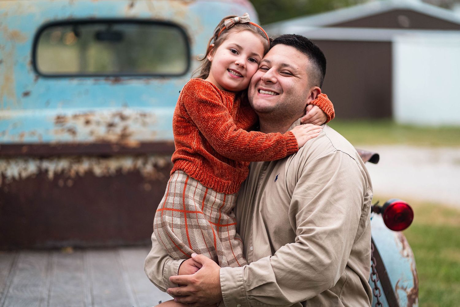 A dad and daugther look at the camera and smile during a family photo session in Lee's Summit