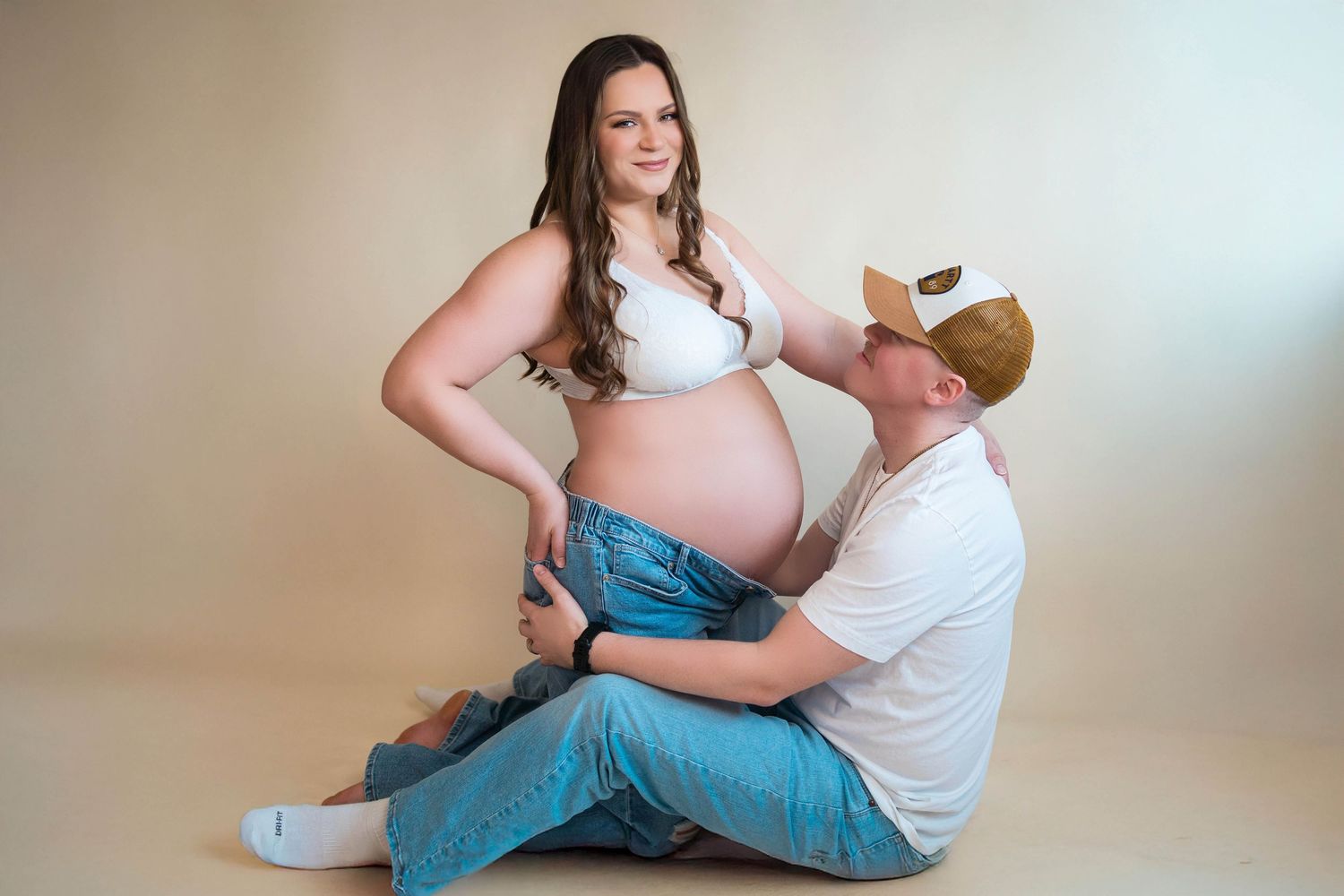 mom and dad sitting on the ground during their maternity photography session in the photographer studio located in Warrensburg, Missouri