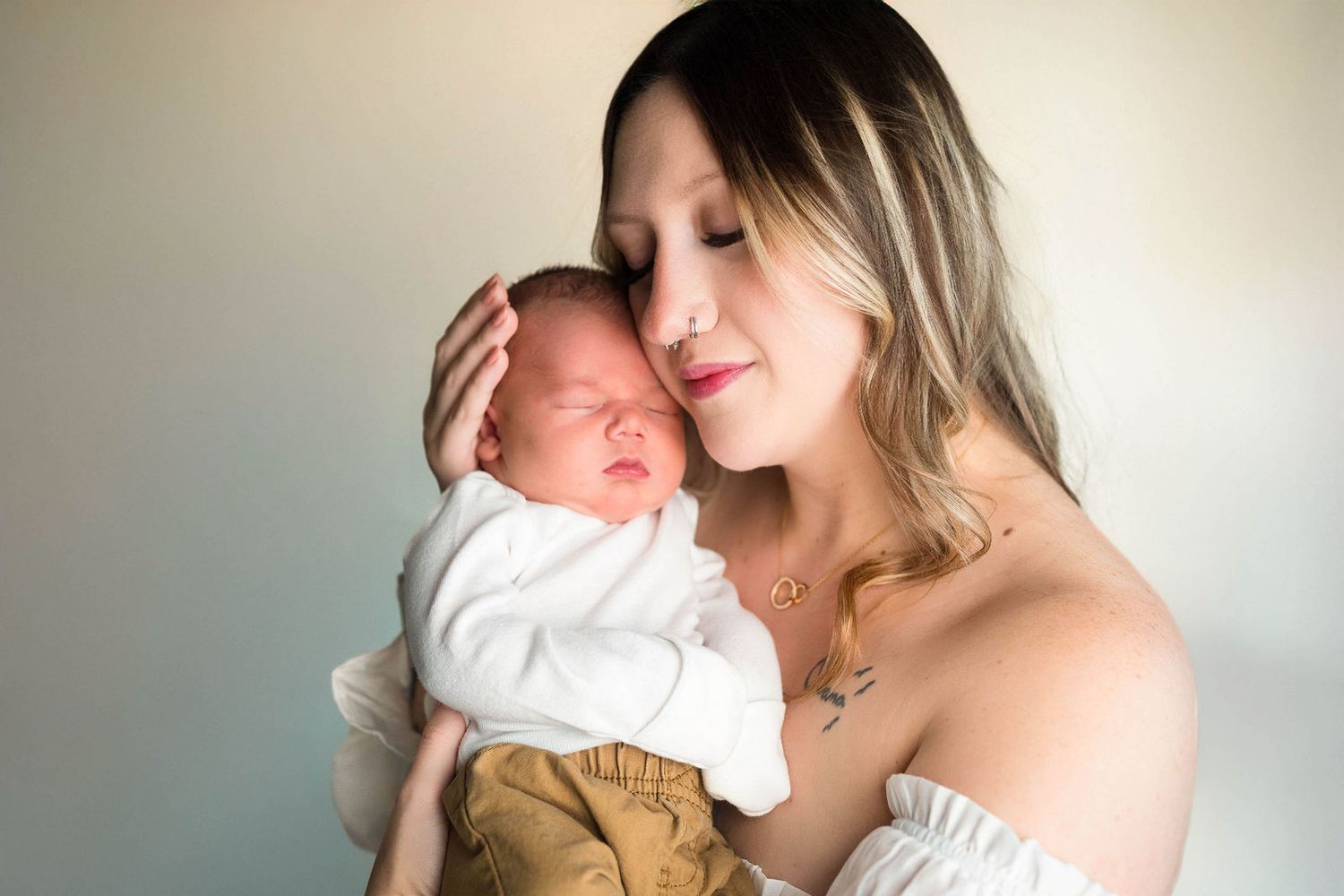 a mom and baby close eyes during their newborn photography session in Lee's Summit