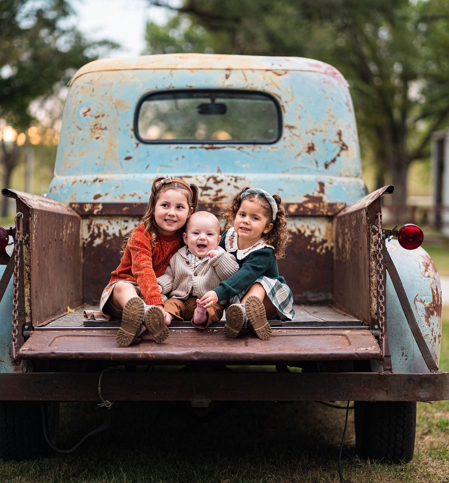 Three kids laugh on the back of the truck during a family photoshoot in Warrensburg