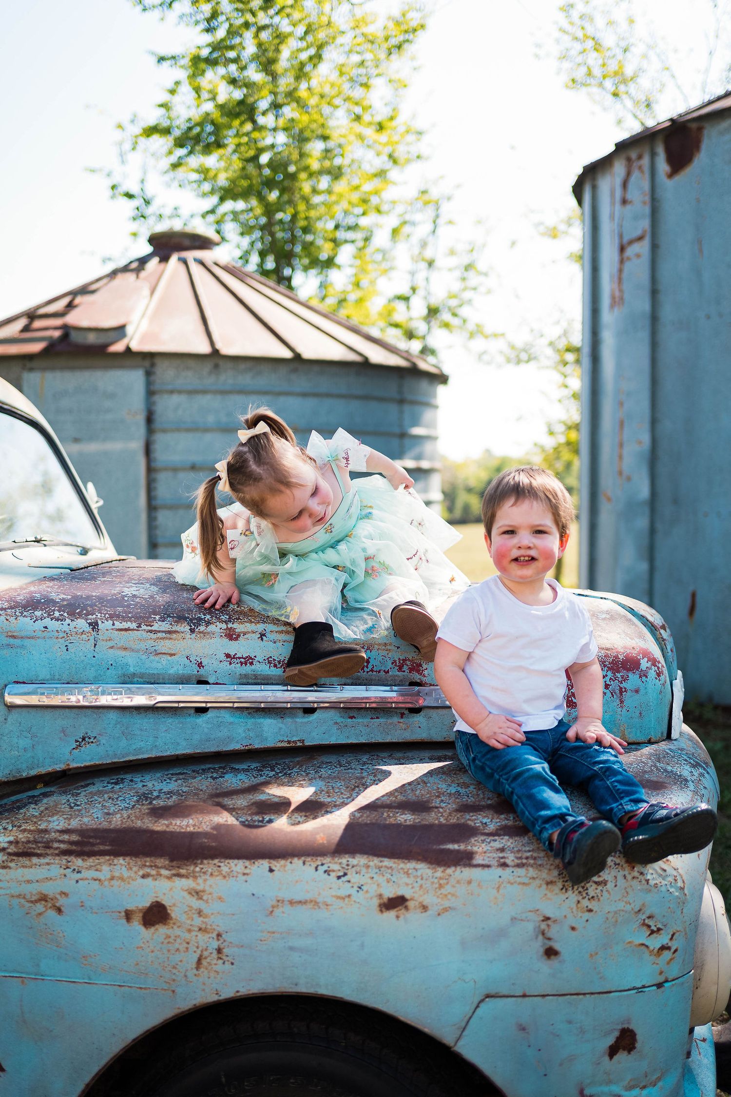 siblings play on a truck during their family photos in Warrensburg