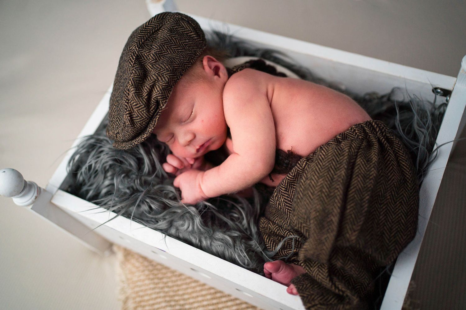 a baby cuddles into the bed prop during his newborn session in the photographer's studio located in Warrensburg