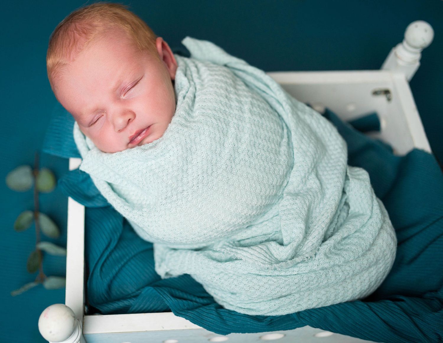 A baby sleeps and is snuggled up during his newborn session in the photographers studio in Warrensburg