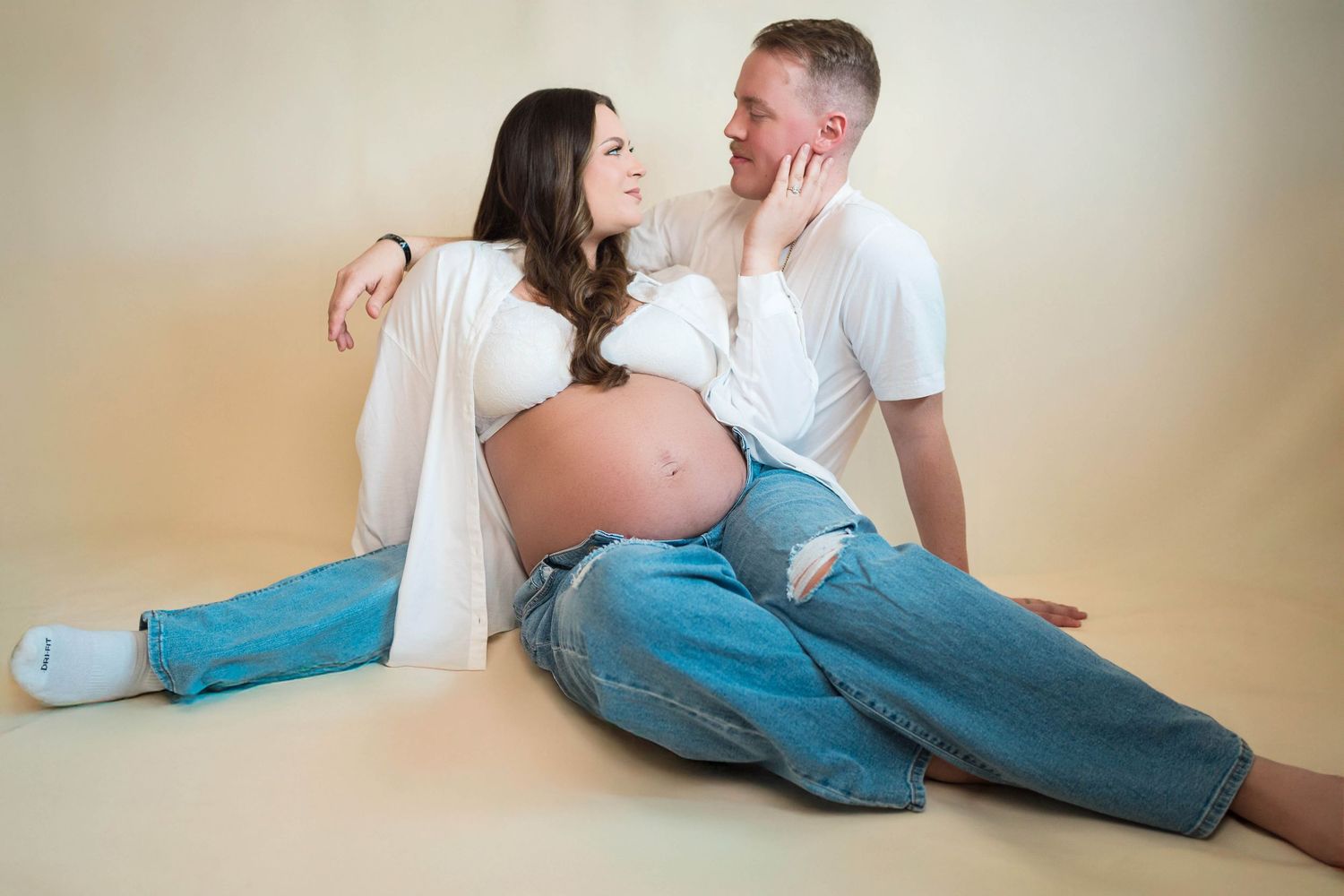 A couple sits together and embraces one another during their maternity session in Warrensburg, MO
