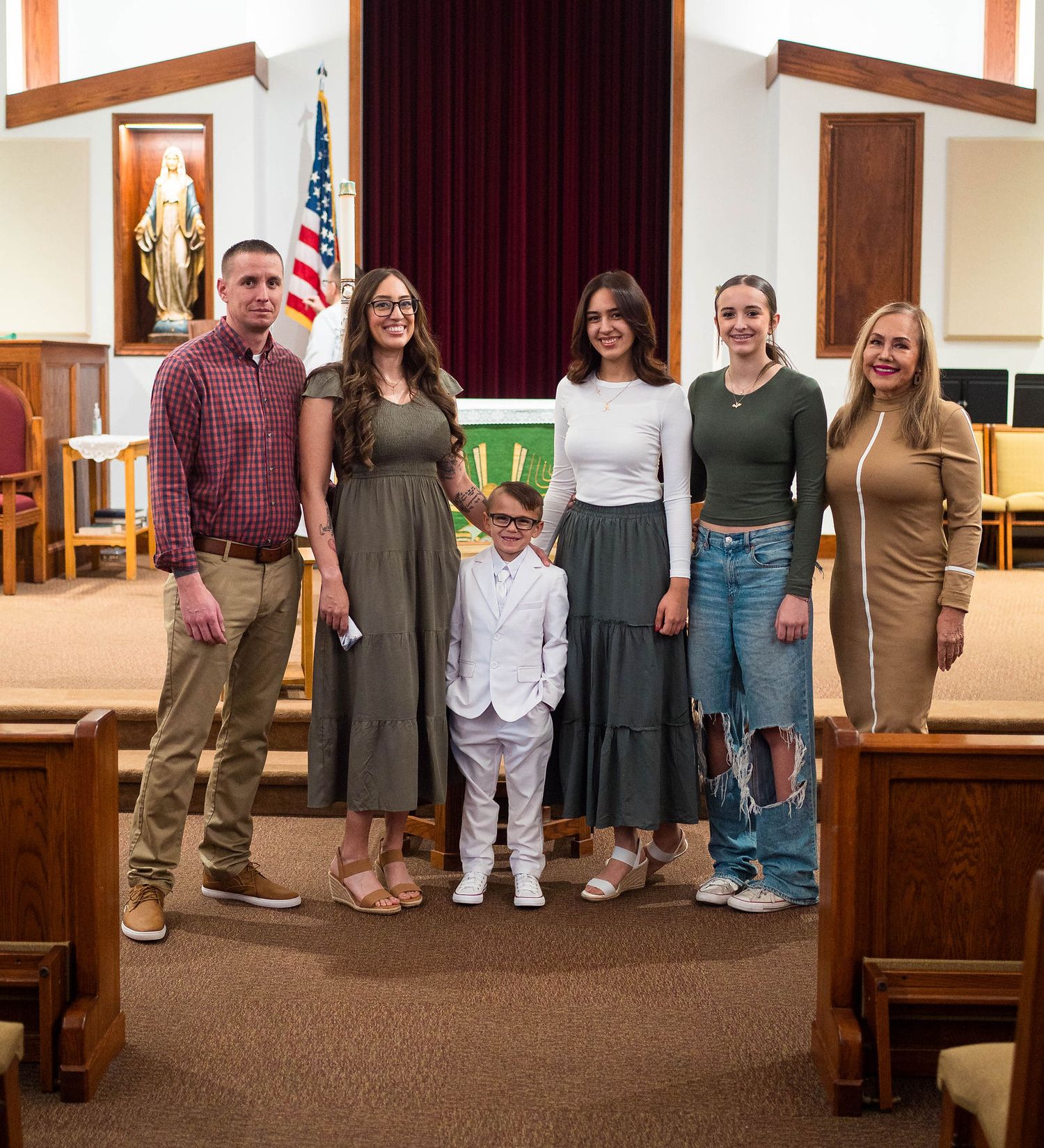 A family smiles at the camera after a child's baptism located in Knob Noster
