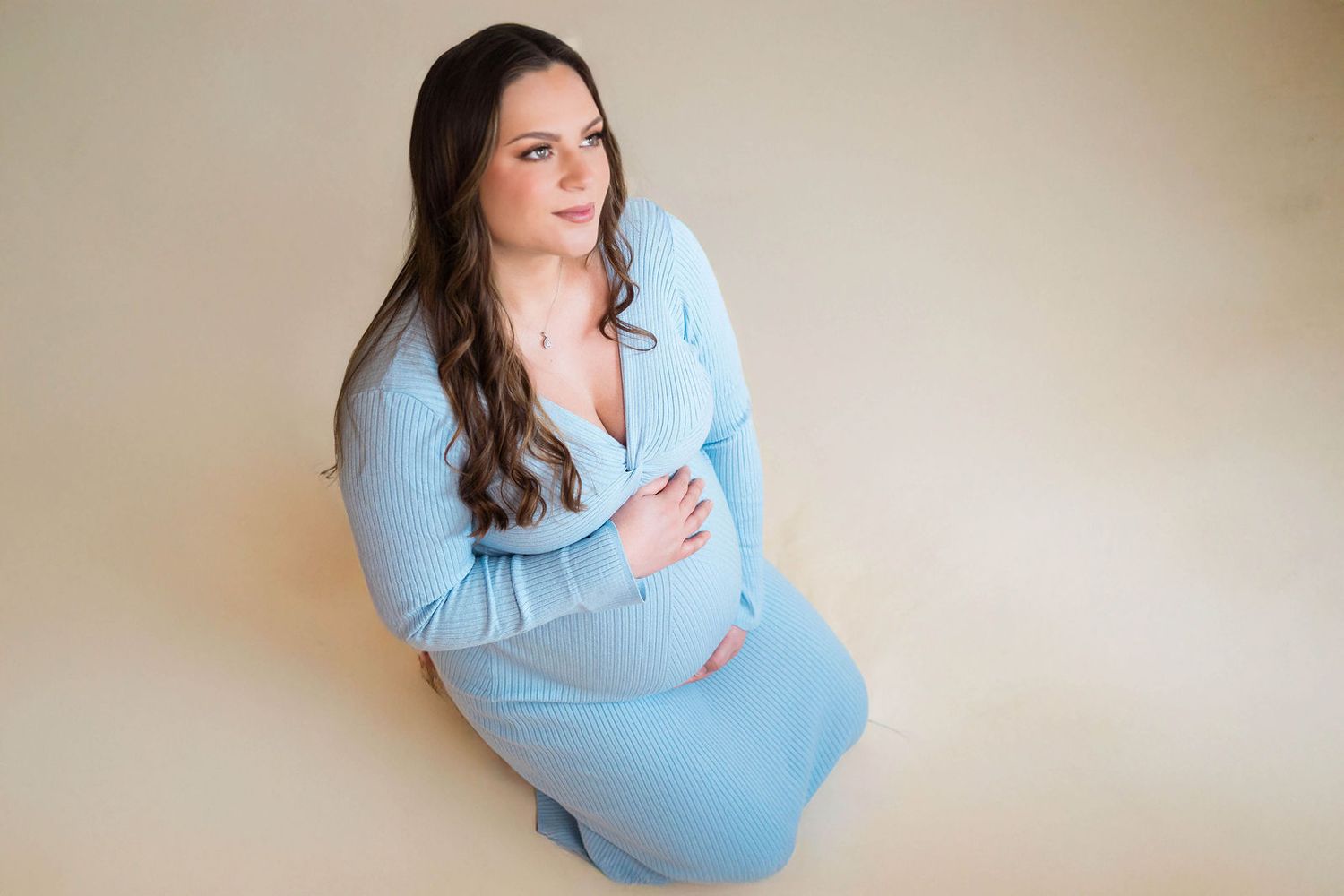 A pregnant mom embraces her bump during her portrait maternity photography session in the photographers home in Warrensburg