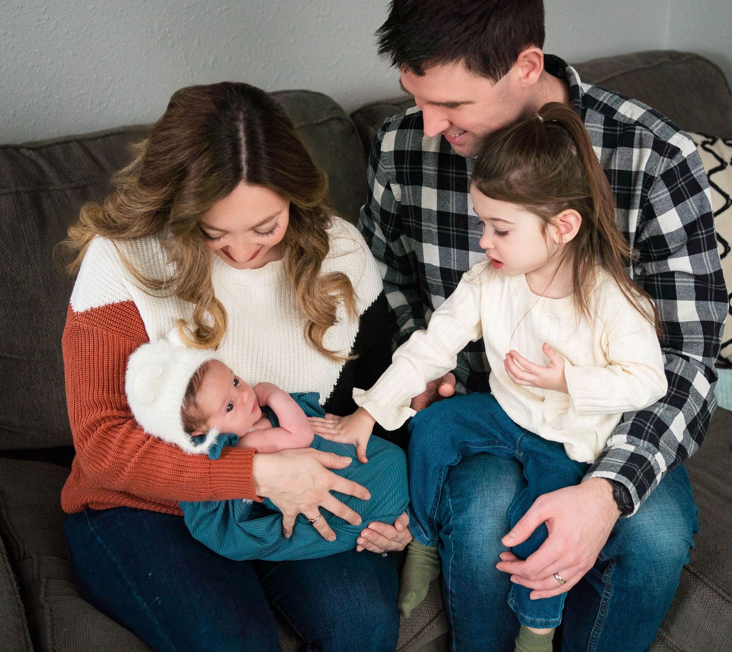 A family smile and look down at baby during a newborn photography session located in Knob Noster