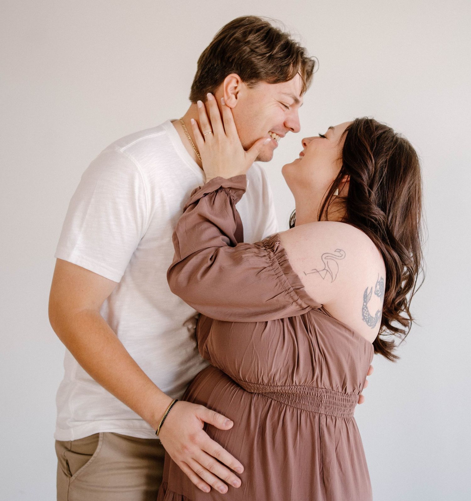 A couple embraces and laughs during their maternity session in-studio in warrensburg, mo
