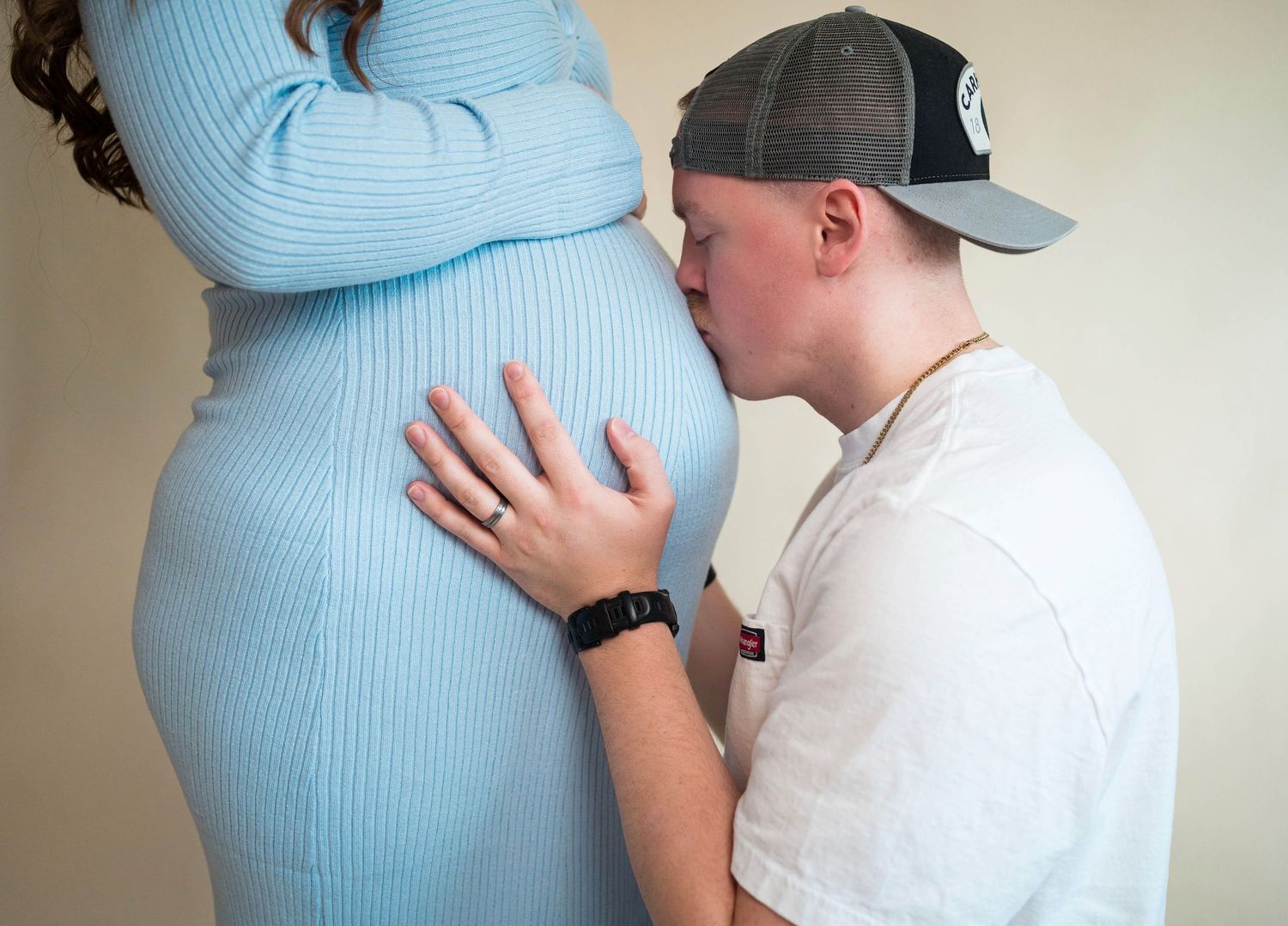 Dad kisses moms pregnant belly during in-studio maternity session in Warrensburg, MO