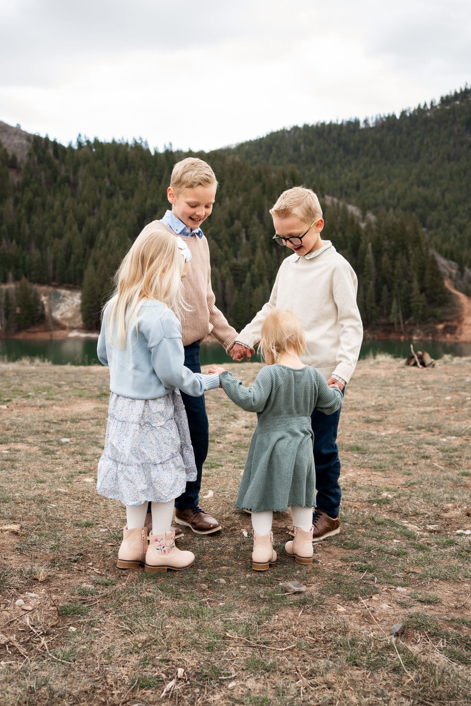 Children in coordinated outfits play together in a circle on a mountain overlook.