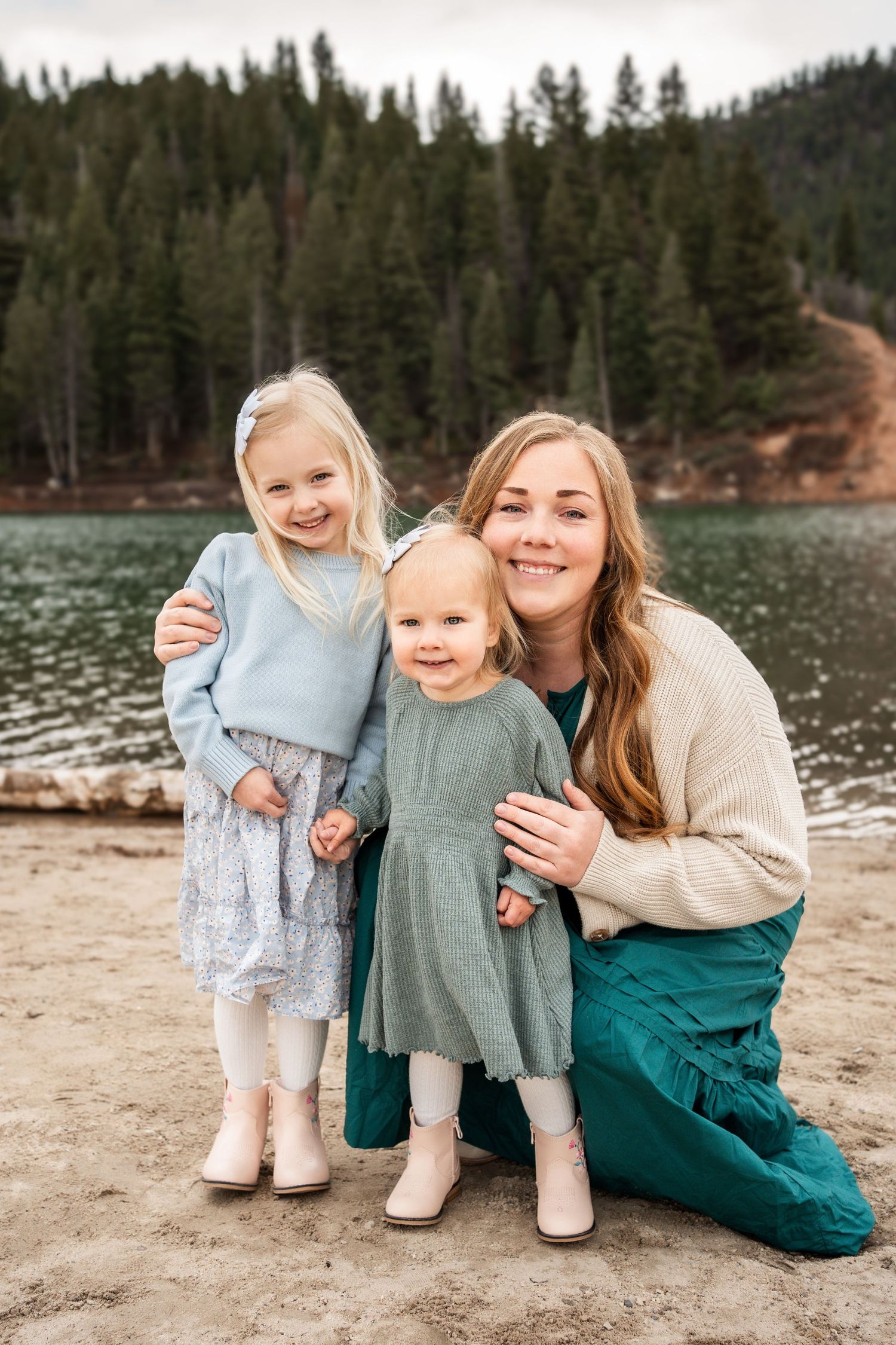 A family enjoys a peaceful moment together by a serene lake surrounded by evergreen forest.