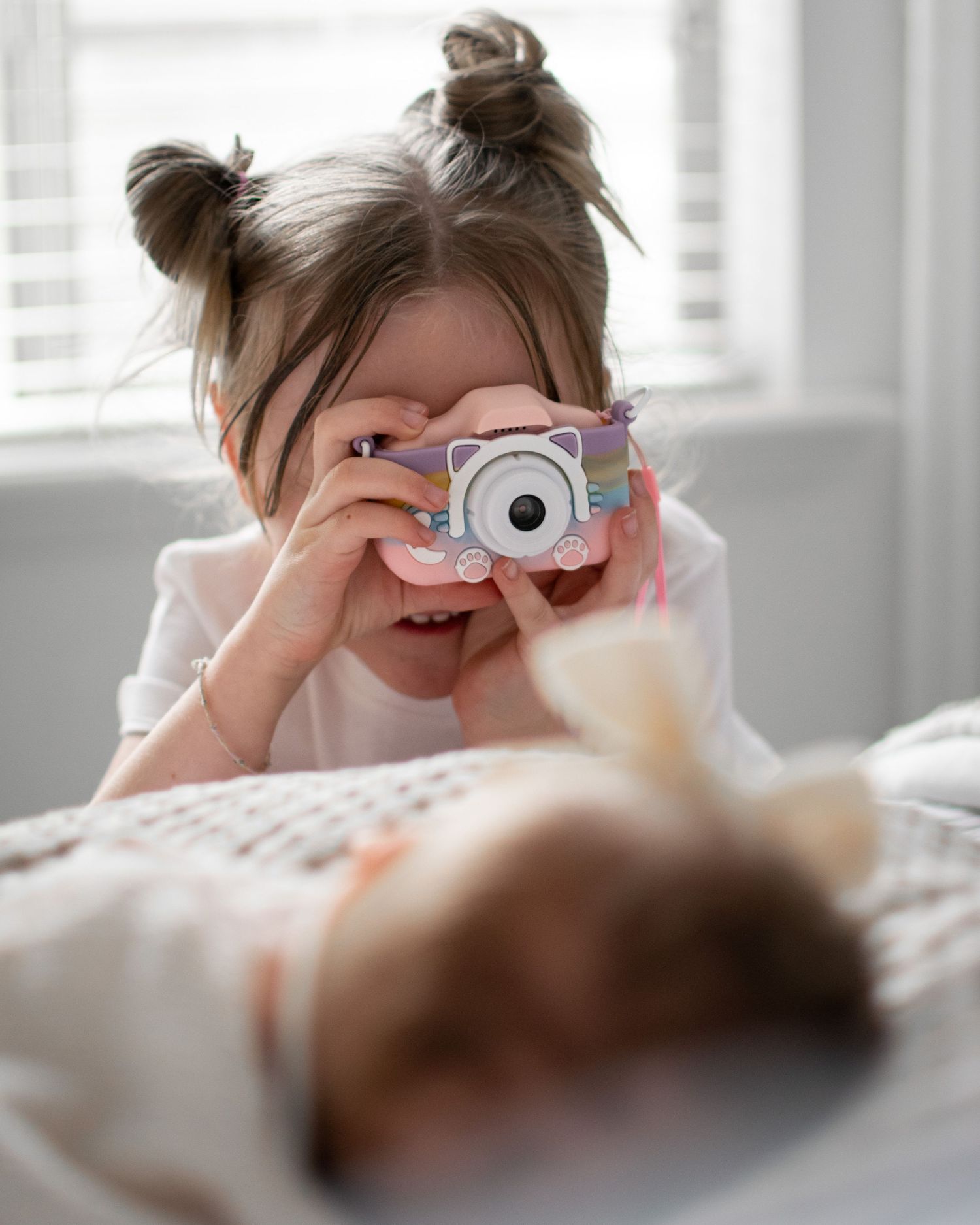 Child holds camera while taking photos in bright sunlit room.