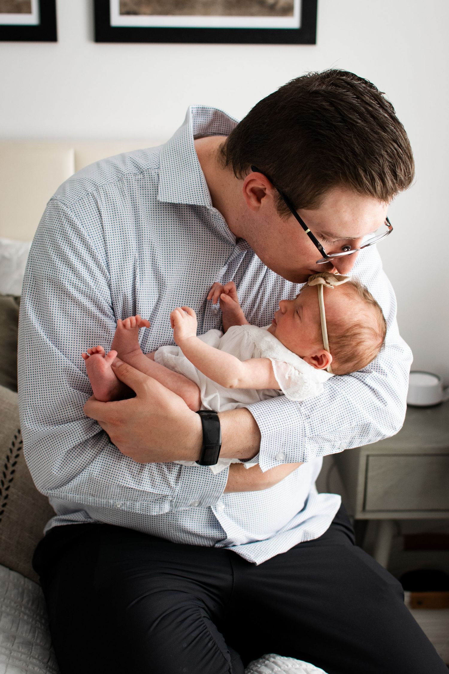 Parent in light blue shirt tenderly holding and bonding with infant.