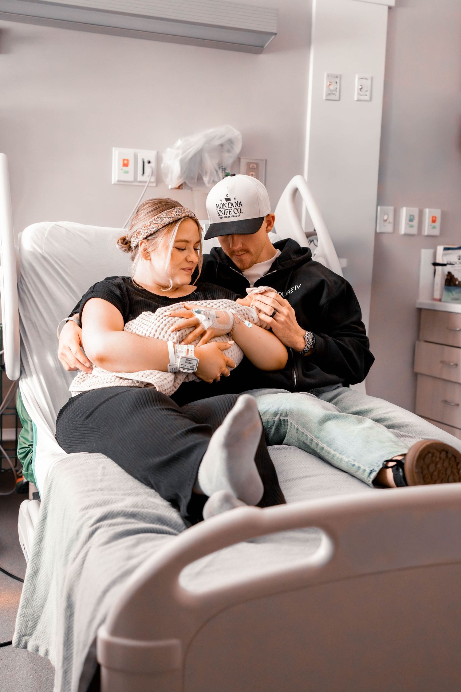 New parents share a tender moment with their newborn baby in a hospital room after delivery.